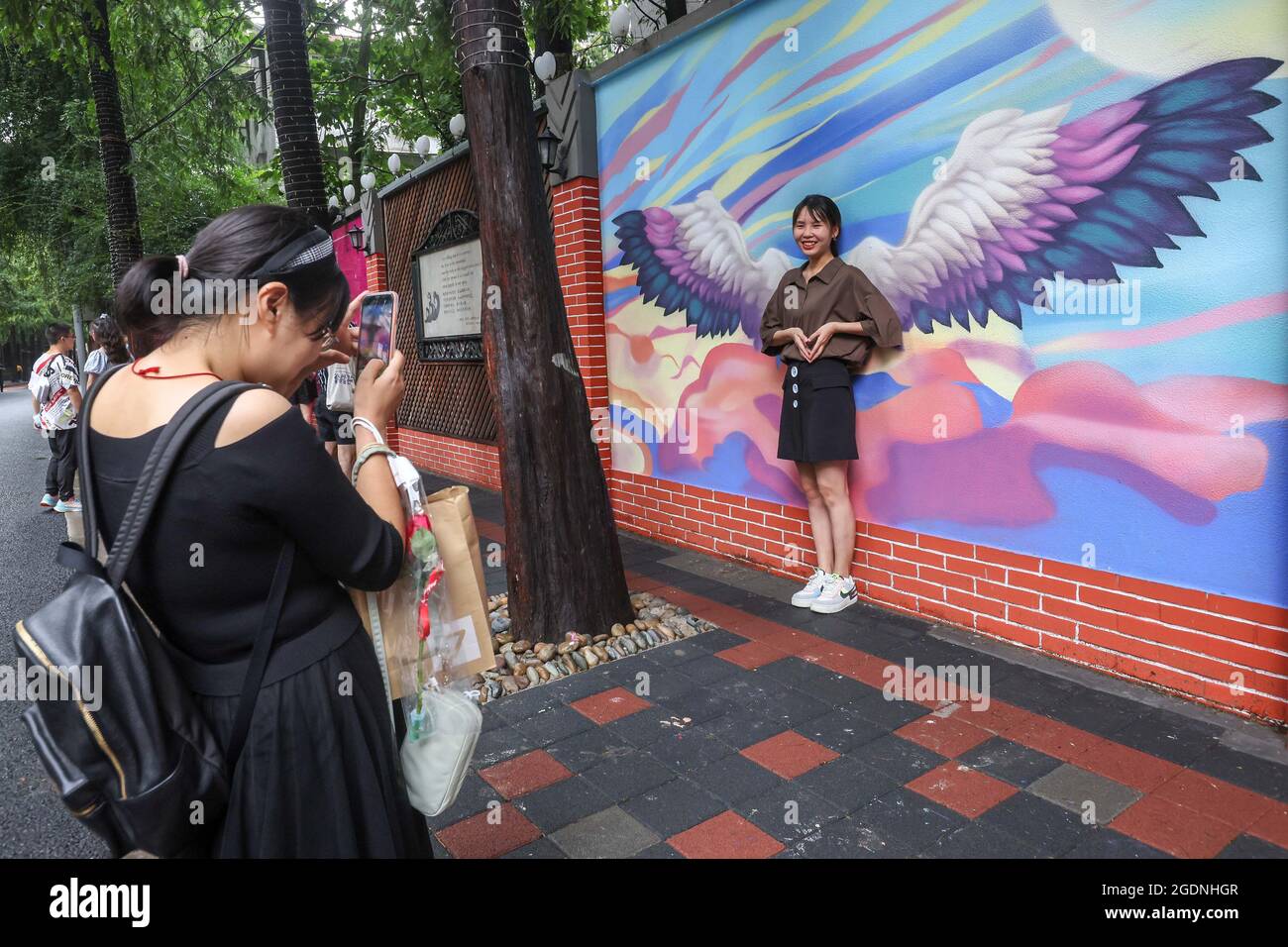 Shanghai, Chine. 14 août 2021. Une femme pose pour des photos devant une peinture murale sur le thème de l'art romantique à Shanghai, en Chine orientale, le 14 août 2021. Le festival Qixi, ou la Saint-Valentin chinoise, tombe le 14 août de cette année. Crédit : Wang Xiang/Xinhua/Alay Live News Banque D'Images