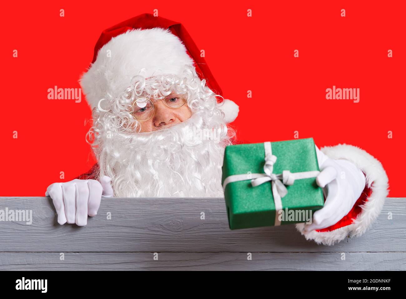 Le Père Noël tient la boîte-cadeau verte dans sa main. Concept de vente de Noël Banque D'Images