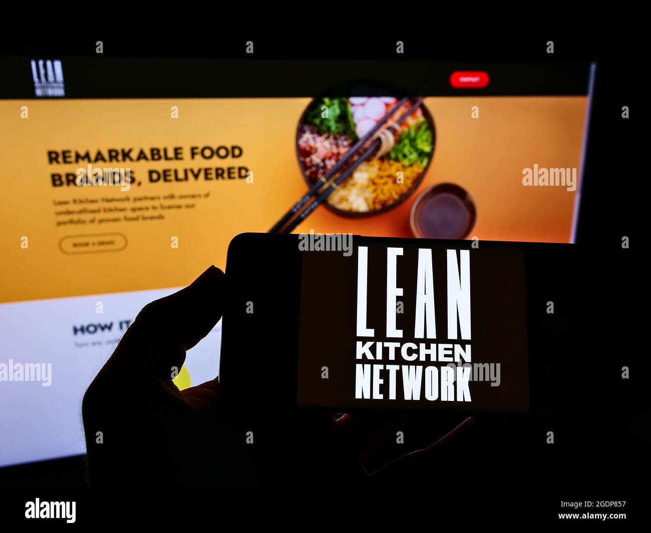Personne tenant un smartphone avec le logo de la société britannique Lean Kitchen Network Limited (LKN) à l'écran devant le site Web. Mise au point sur l'affichage du téléphone. Banque D'Images