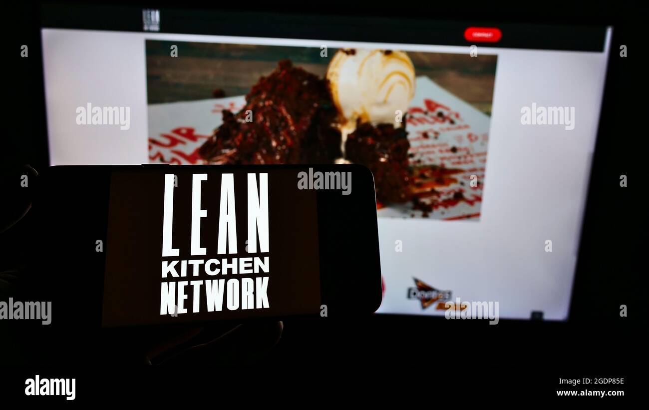 Personne tenant un téléphone portable avec le logo de la société britannique Lean Kitchen Network Limited (LKN) à l'écran devant la page Web. Mise au point sur l'affichage du téléphone. Banque D'Images