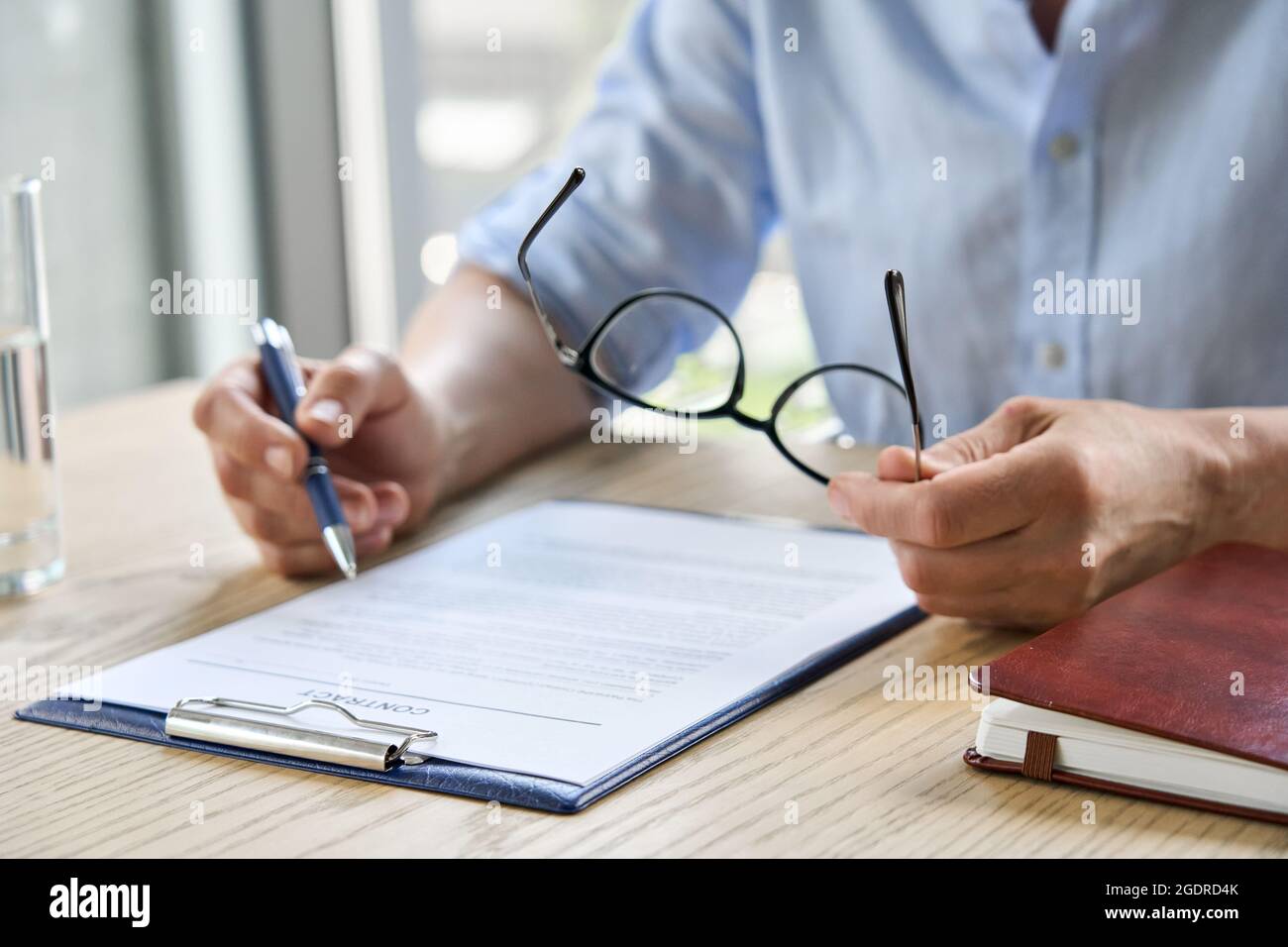 Une femme d'affaires avocate a lu le contrat de partenariat à la table tenant des lunettes. Gros plan Banque D'Images