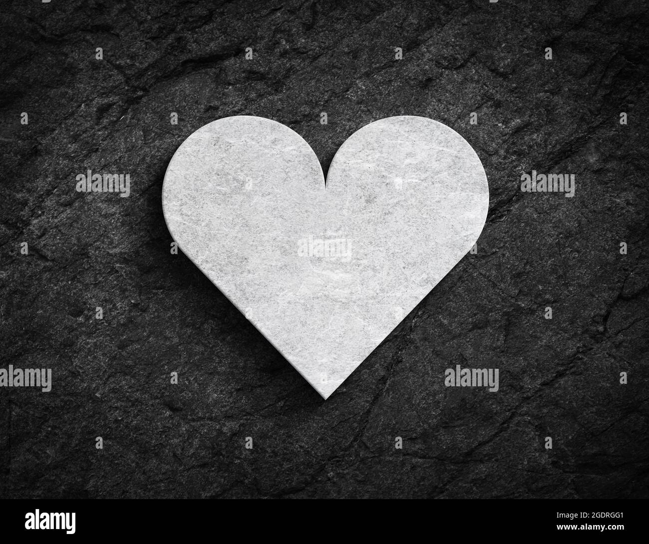 Grand symbole de coeur 3D blanc sur un mur en pierre noir foncé Banque D'Images