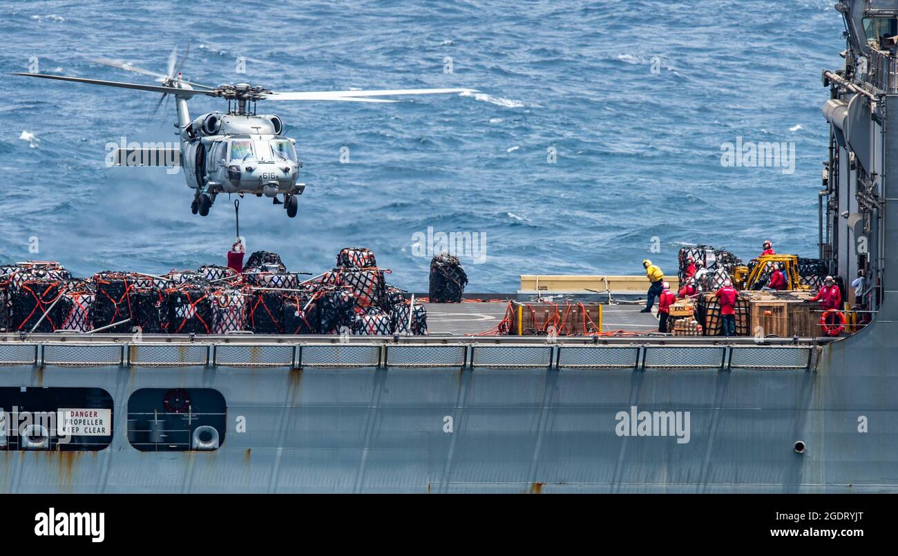 210813-N-BR419-1124 MER D'ARABIE (le 13 août 2021) – un hélicoptère MH-60S Sea Hawk, attaché aux « Falcons d'or » de l'escadron de combat de la mer (HSC) 12, ramasse des fournitures du navire de fret et de munitions de commandement militaire de la force maritime USNS Wally Schirra (T-AKE 8) lors d'une reconstitution verticale en mer d'Arabie, Août 13. Ronald Reagan est déployé dans la zone d'opérations de la 5e flotte des États-Unis à l'appui des opérations navales afin d'assurer la stabilité et la sécurité maritimes dans la région centrale, reliant la Méditerranée et le Pacifique par l'océan Indien occidental et trois points d'étranglement stratégiques. ( Banque D'Images