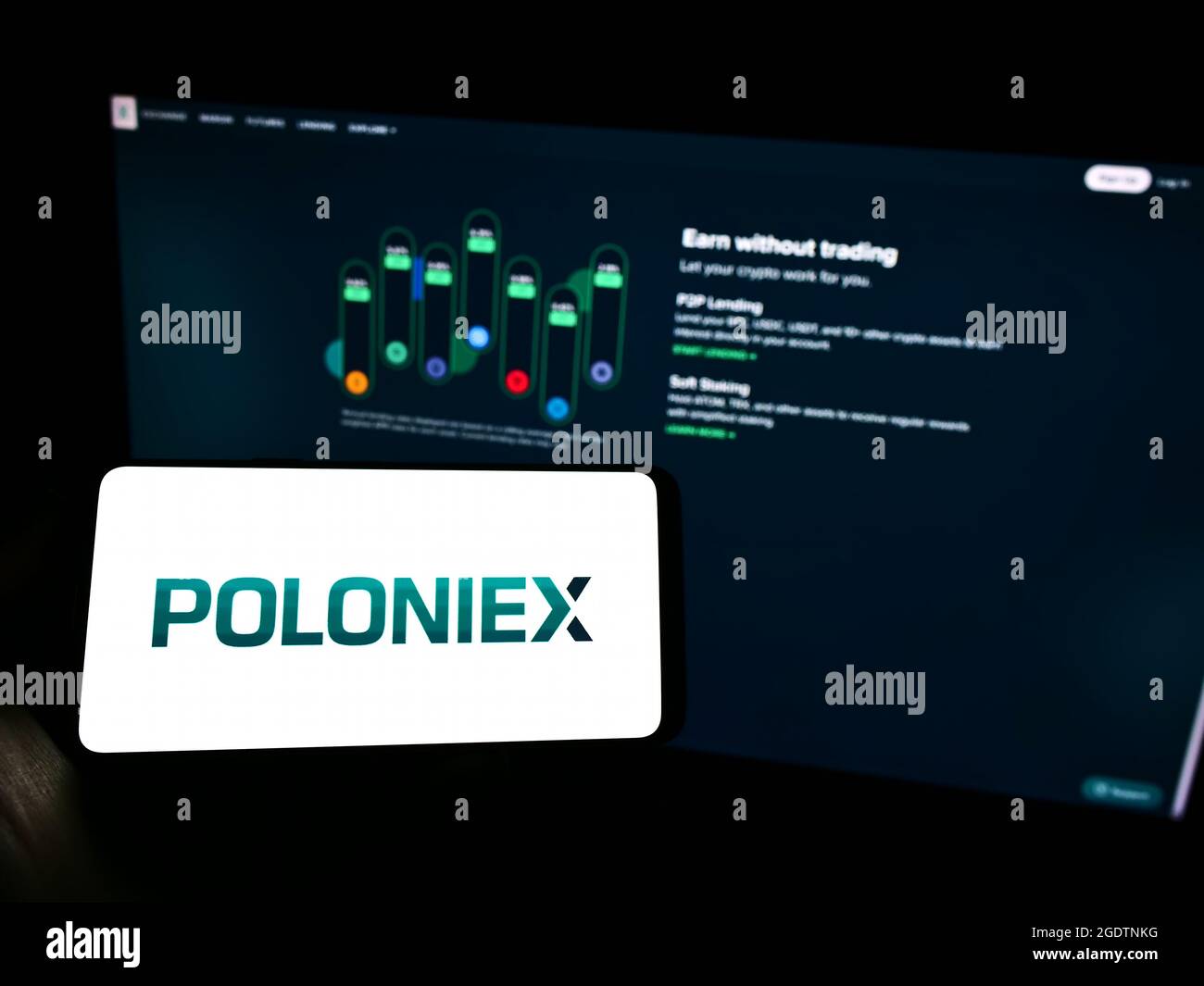 Personne détenant un téléphone portable avec le logo de la société d'échange de crypto-monnaies Poloniex Inc. À l'écran devant la page Web des affaires. Mise au point sur l'affichage du téléphone. Banque D'Images