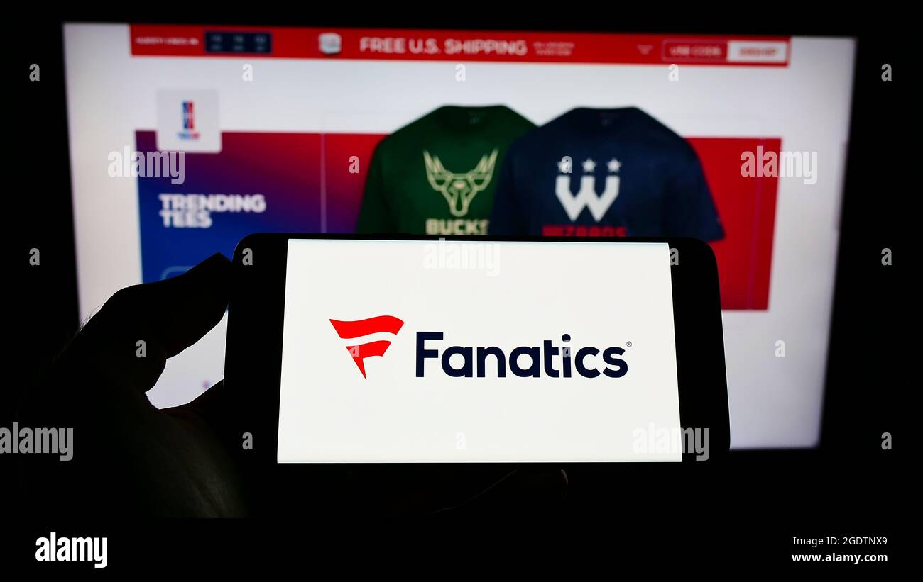 Personne tenant le téléphone portable avec le logo de US en ligne sportswear détaillant fanatics Inc. À l'écran en face de la page Web d'affaires. Mise au point sur l'affichage du téléphone. Banque D'Images