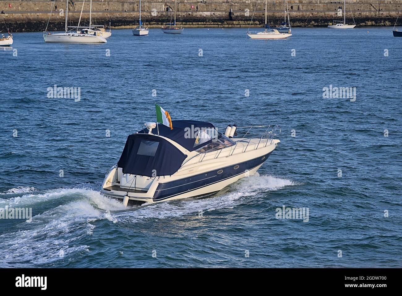 Belle vue en soirée d'un seul bateau mobile sur l'eau avec drapeau irlandais dans le port de Dun Laoghaire, Dublin, Irlande. Mise au point douce et sélectionnée Banque D'Images
