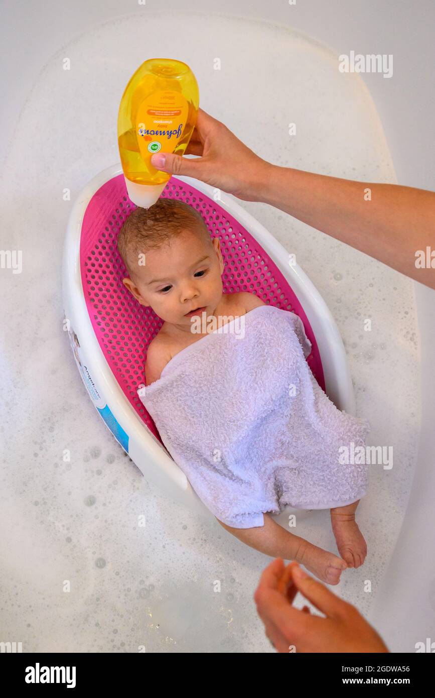 Bébé dans un bain ayant un lavage de cheveux avec le shampooing de bébé de Johnson Banque D'Images