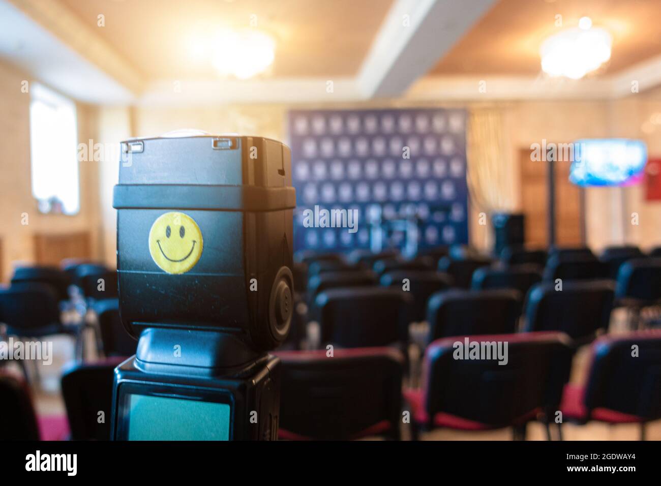 Flash portable de l'appareil photo contre l'arrière-plan de la salle pour les conférences de presse. L'émoticône smiley est bloquée sur le flash. Banque D'Images