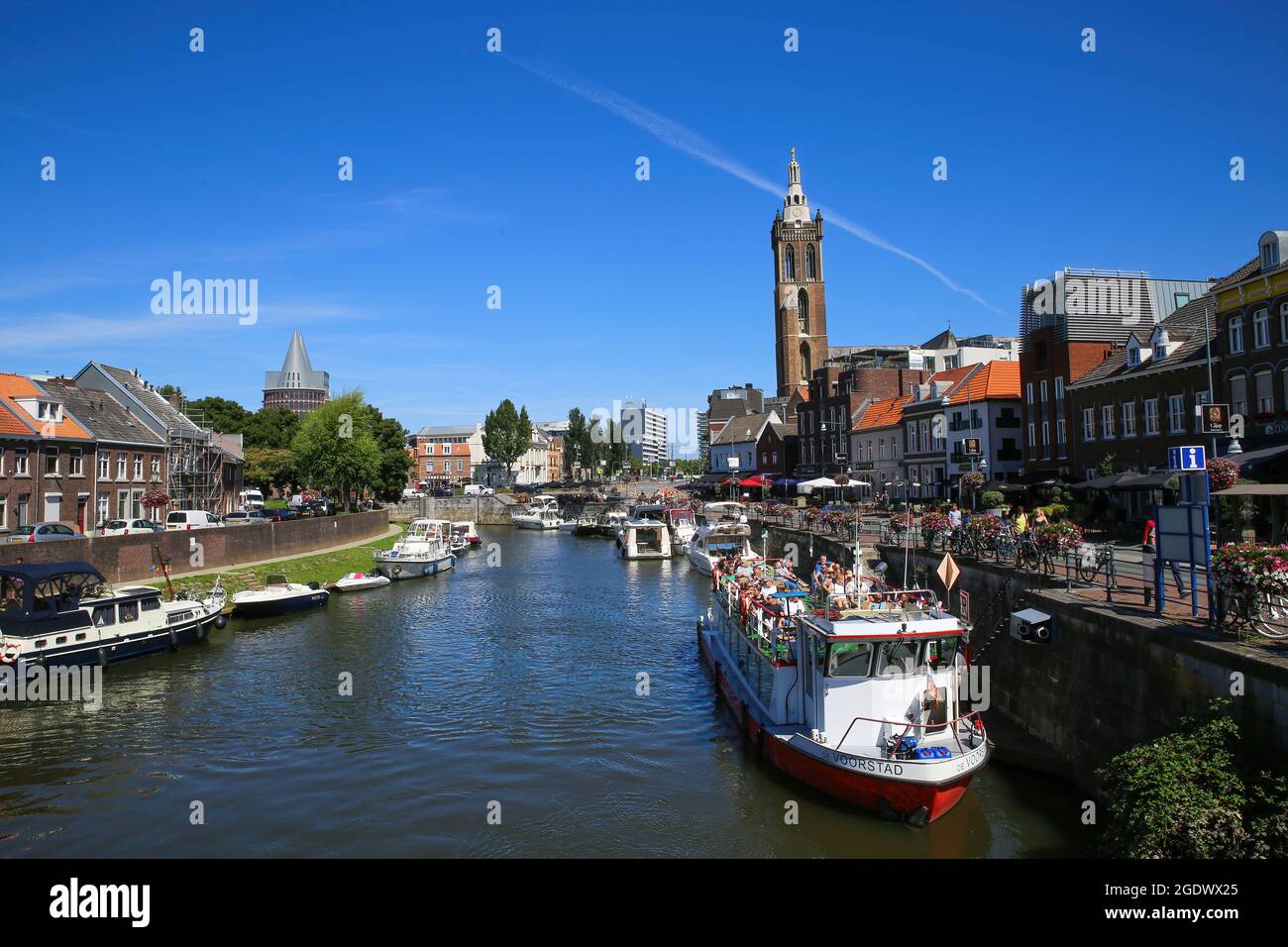 Roermond, pays-Bas - juillet 9. 2021: Vue sur le canal d'eau hollandais animé avec paysage urbain et ancienne tour d'église contre ciel bleu d'été Banque D'Images