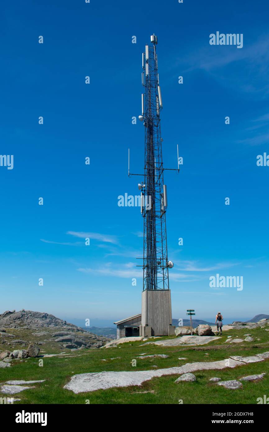 Randonneur à côté de la tour cellulaire de téléphone mobile au-dessus des montagnes rurales en Europe (Norvège), avec fjords en arrière-plan Banque D'Images
