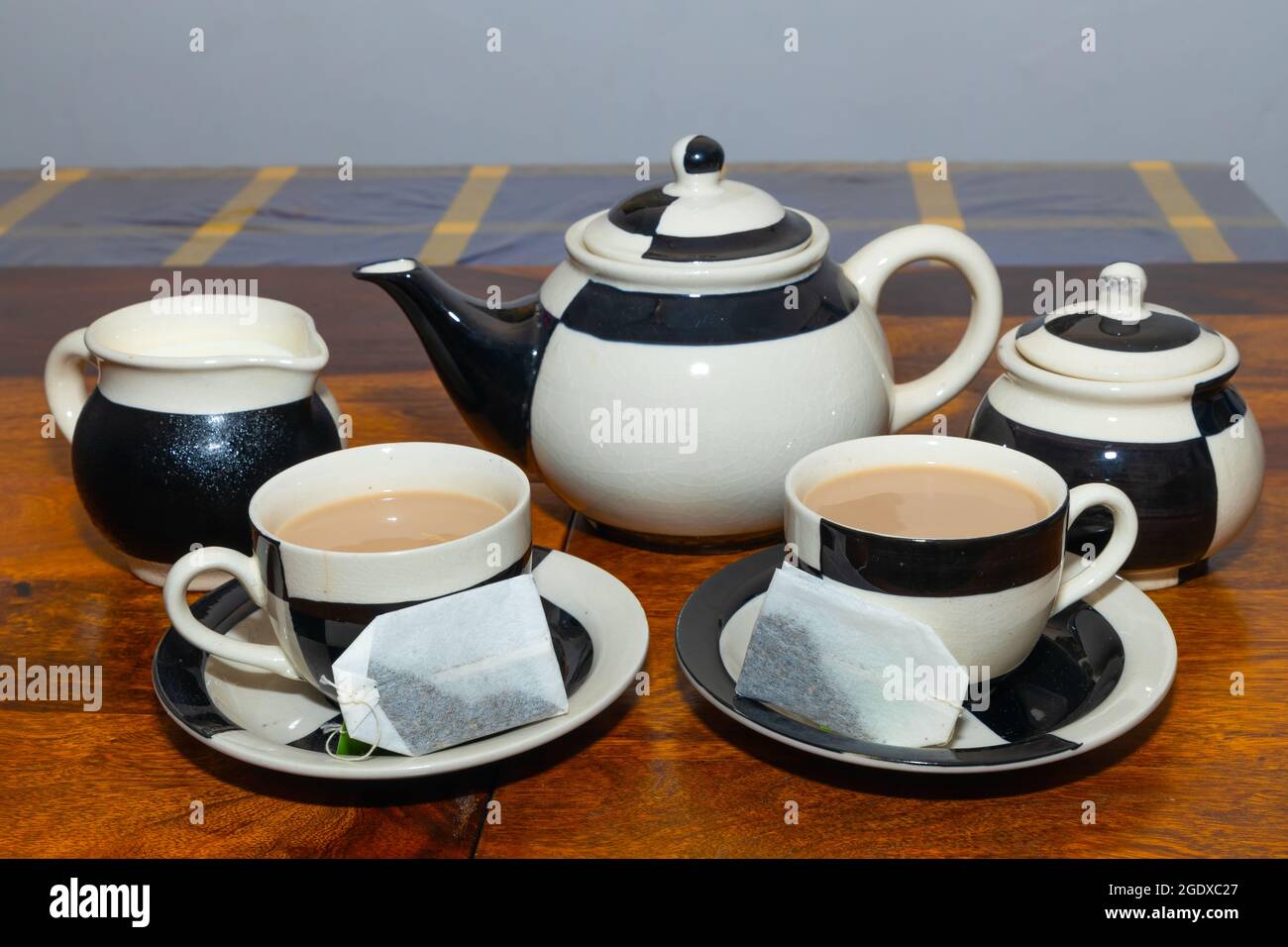 Théière avec tasse et soucoupe au design noir et blanc sur une table en bois Banque D'Images