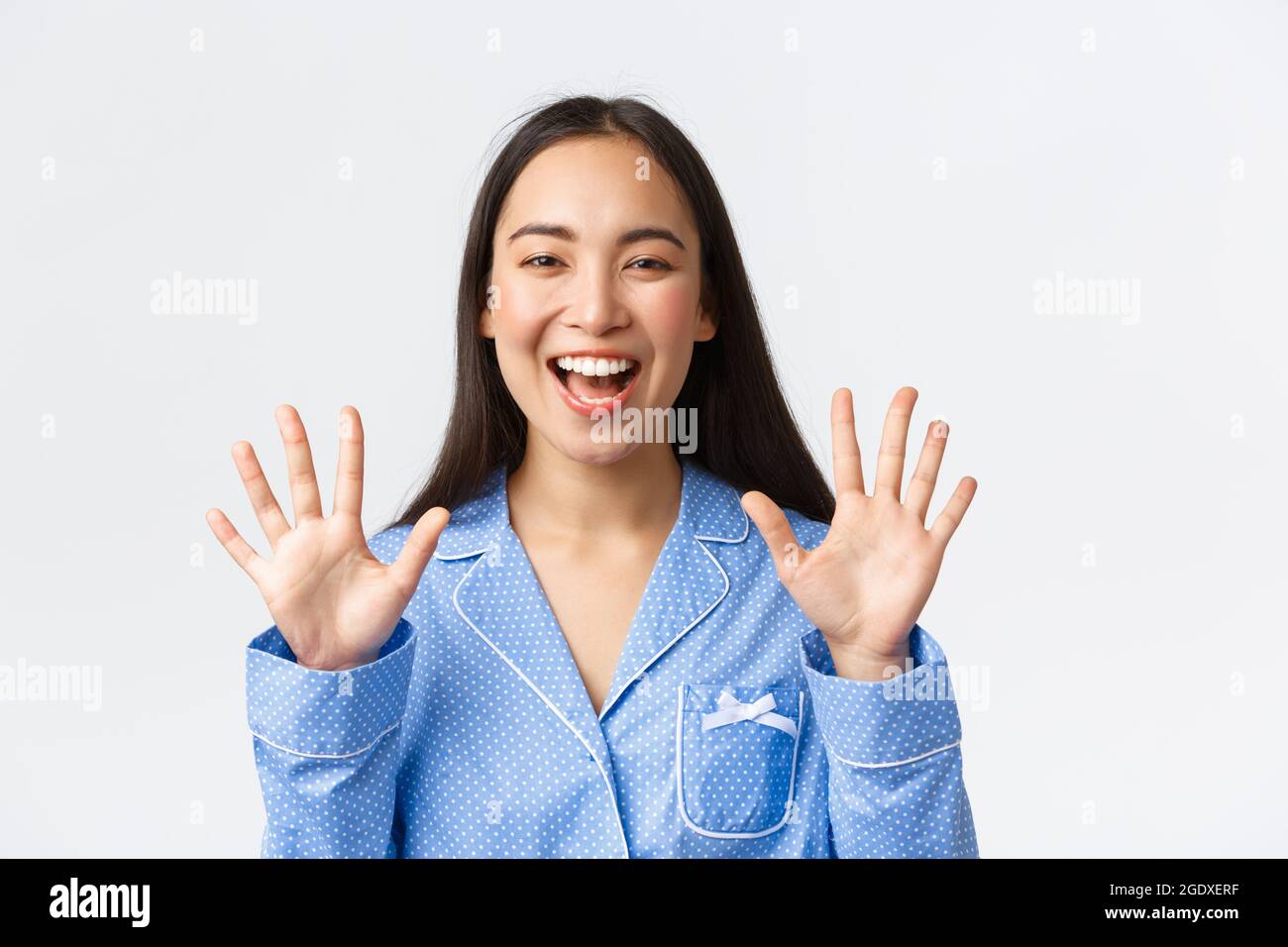 Gros plan de la femme asiatique attrayante et heureuse de pyjama bleu montrant dix doigts et des dents blanches souriantes, expliquer les règles principales ou faire l'ordre, debout Banque D'Images