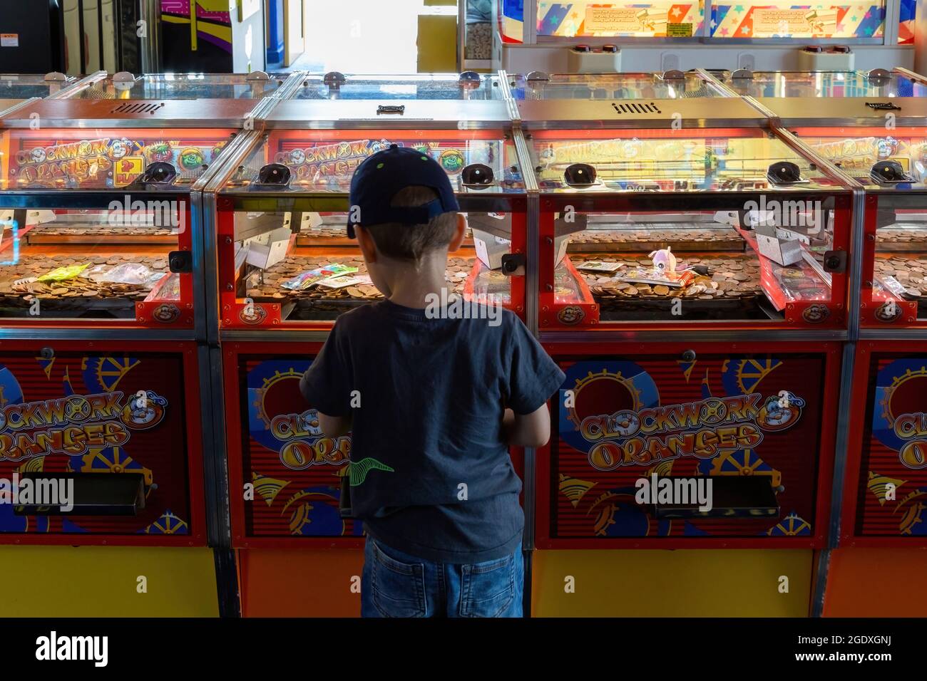 08-12-2021 Portsmouth, Hampshire, Royaume-Uni UN petit garçon jouant les jeux d'arcade de coin Push dans une arcade de divertissement Banque D'Images
