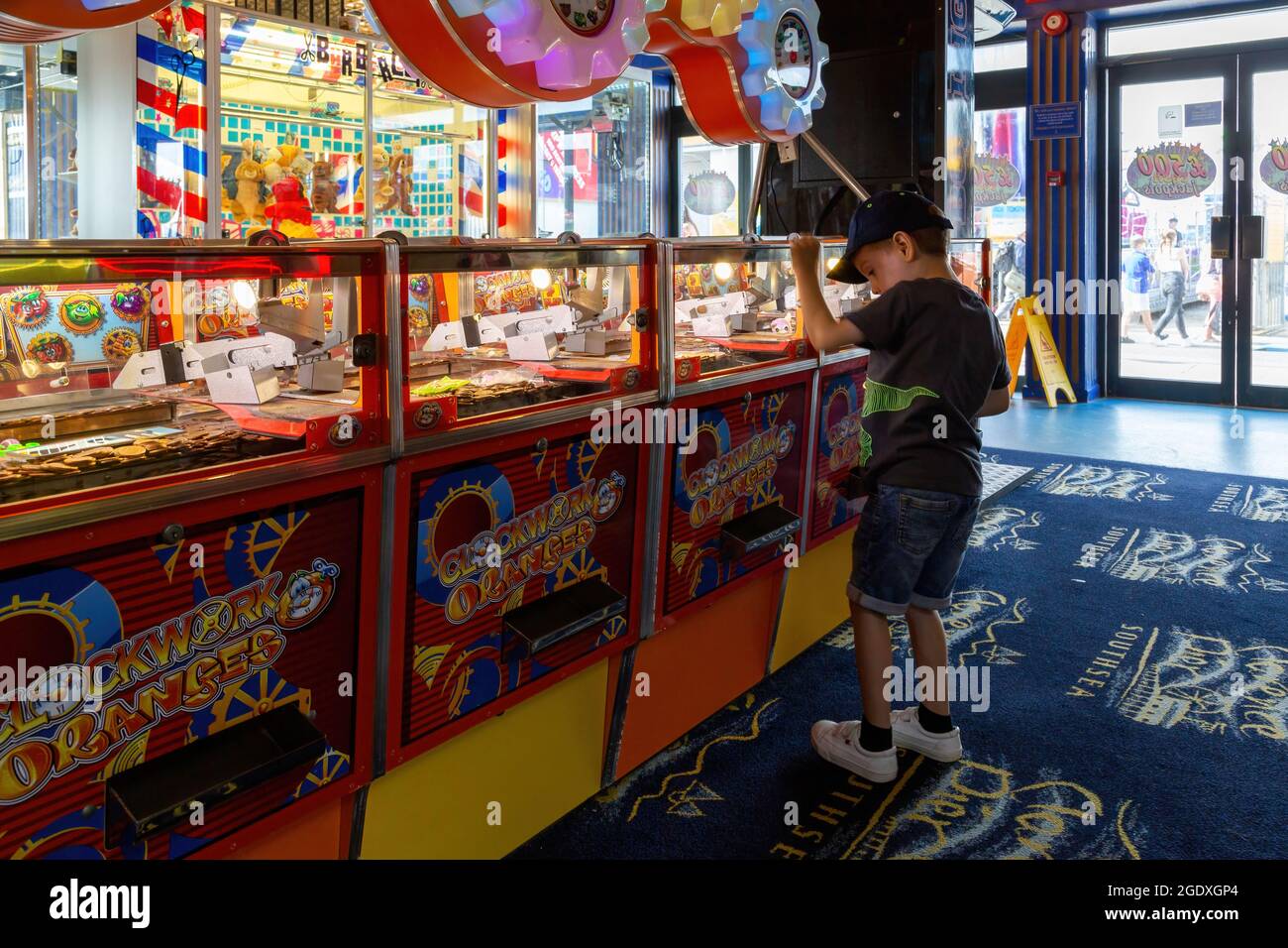 08-12-2021 Portsmouth, Hampshire, Royaume-Uni UN petit garçon jouant les jeux d'arcade push-drop de pièce dans une arcade de divertissement Banque D'Images