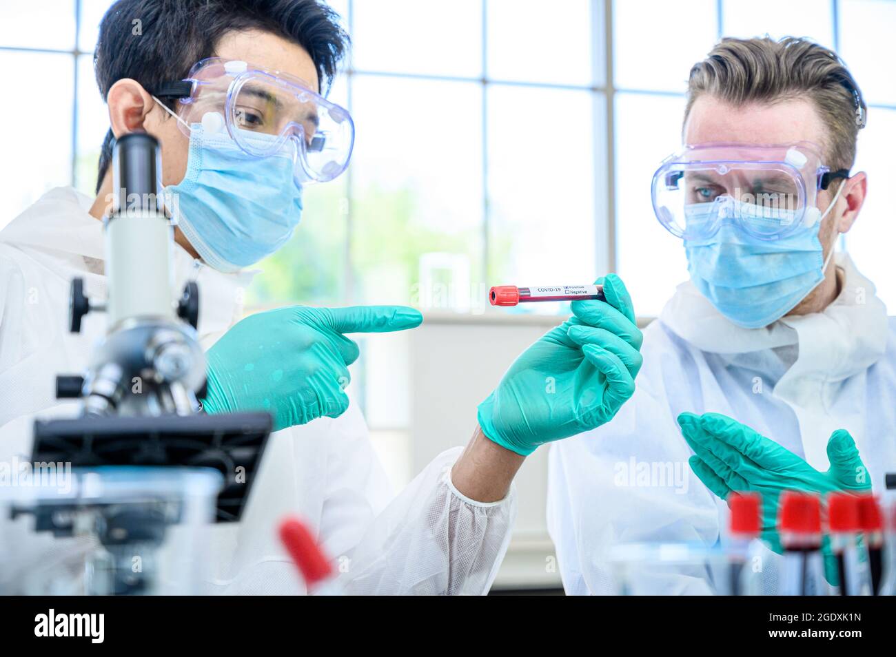 Couple de scientifiques mâles portant une combinaison de protection tenant le vaccin du coronavirus et travaillant avec de nombreux équipements de laboratoire pour la recherche de vaccins en laboratoire. Viru Banque D'Images