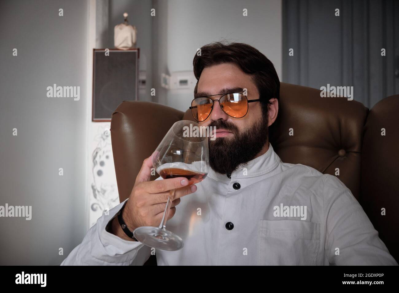 L'homme est assis dans un fauteuil avec un verre de liqueur Banque D'Images