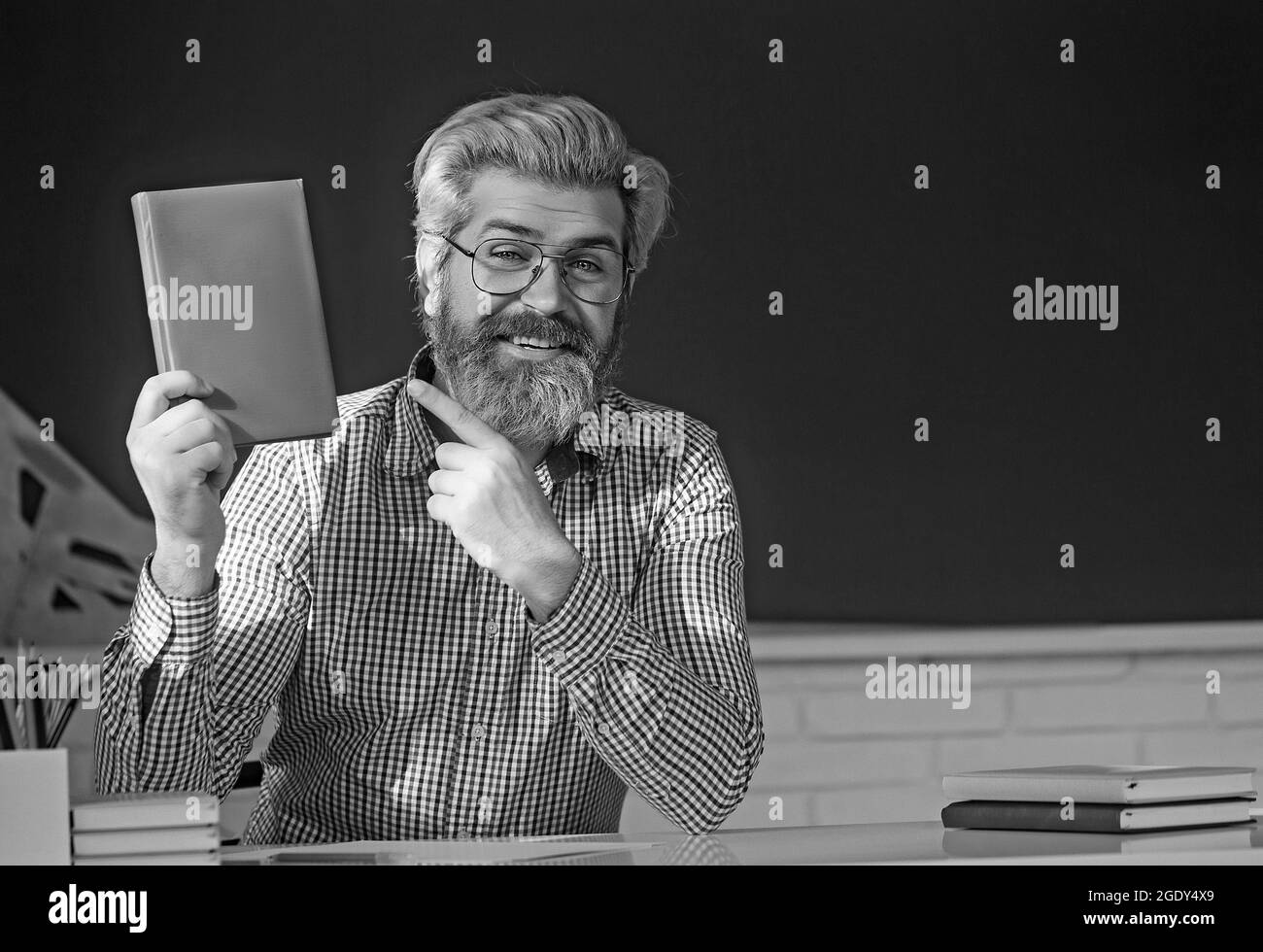 Un professeur barbu et brutal souriant à l'arrière de la salle de classe à l'école élémentaire. Banque D'Images