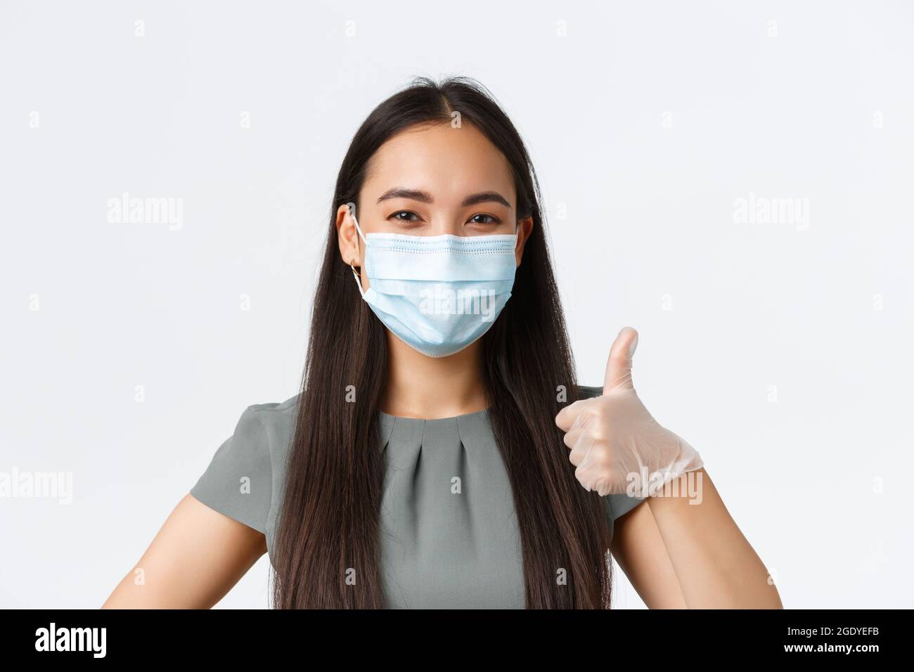 Les propriétaires de petites entreprises, covid-19, prévention des virus concept de mesures. Gros plan de la femme asiatique souriante et confiante dans un masque médical et des gants, montrez vos pouces Banque D'Images