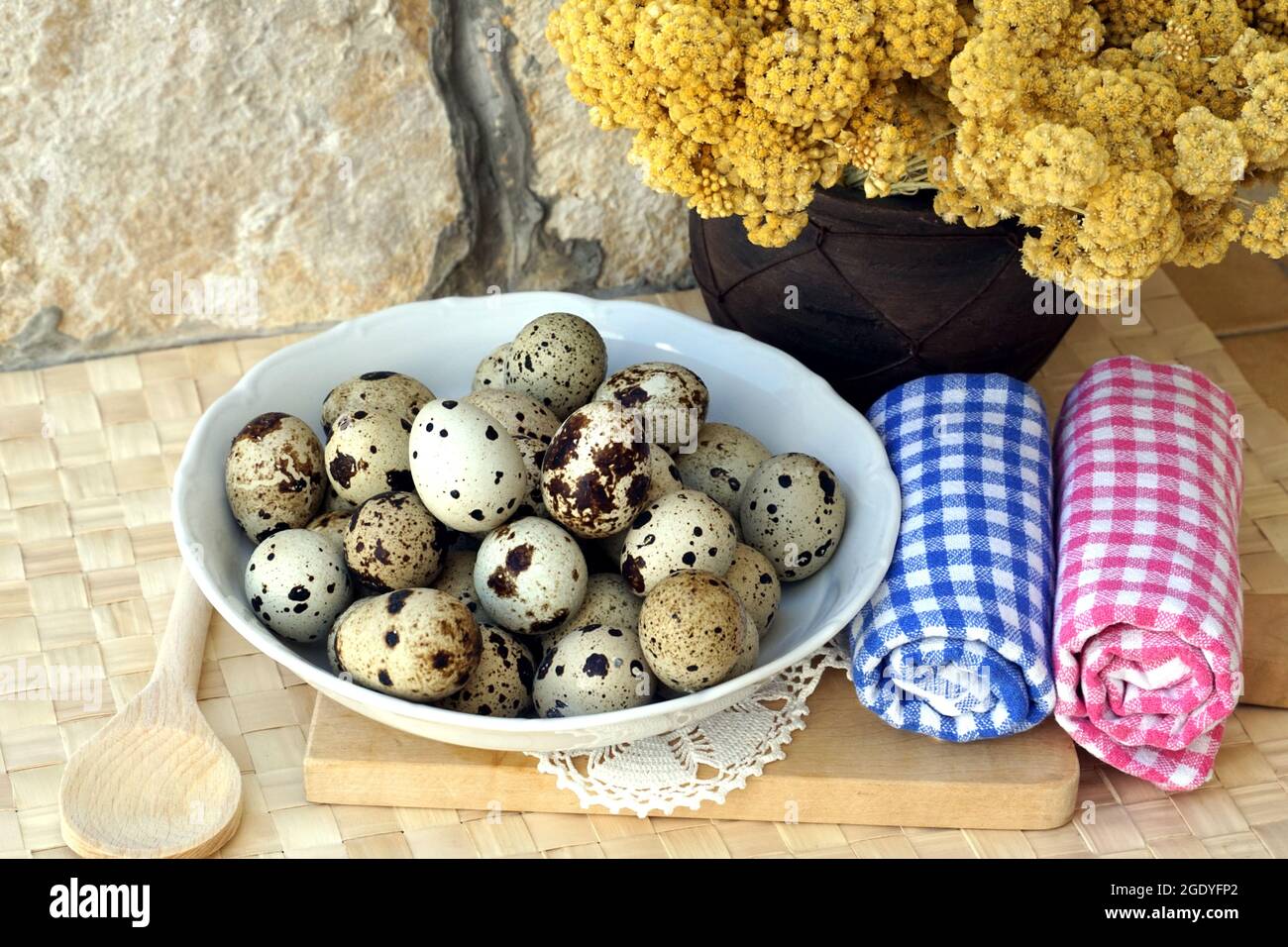 Œufs de caille japonais dans un cadre rustique avec fleurs immortelle dans un vase. Contexte alimentaire rural Banque D'Images