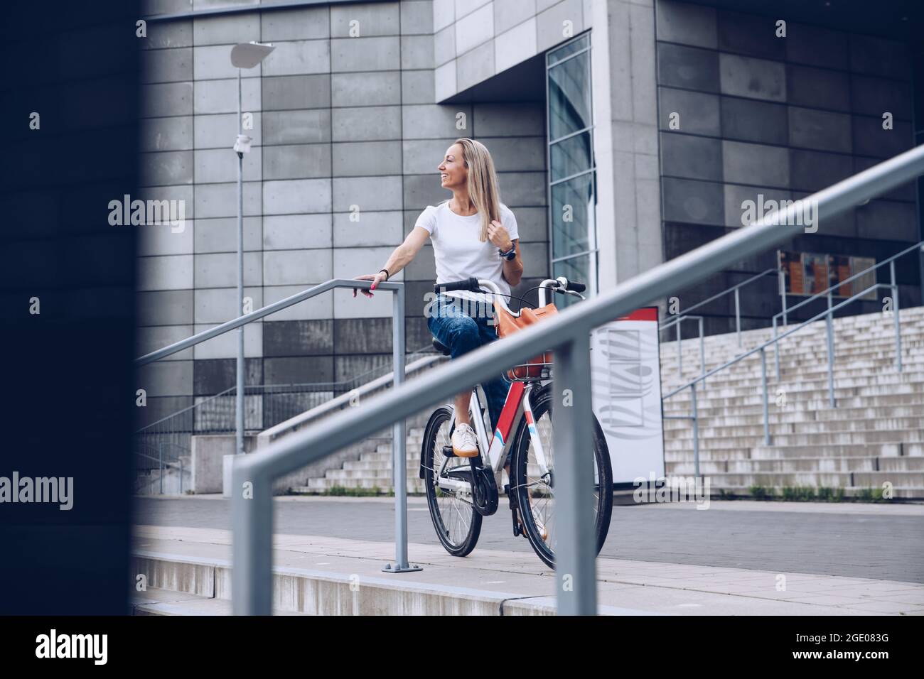 Gaie adulte jeune femme profiter de vélo dans une ville ensoleillée de loisirs en plein air activité dans la ville. Banque D'Images