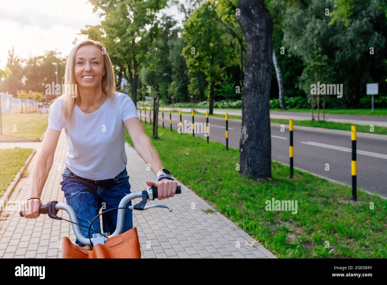 Une jolie jeune femme dans un t-shirt blanc est à vélo de ville. Banque D'Images