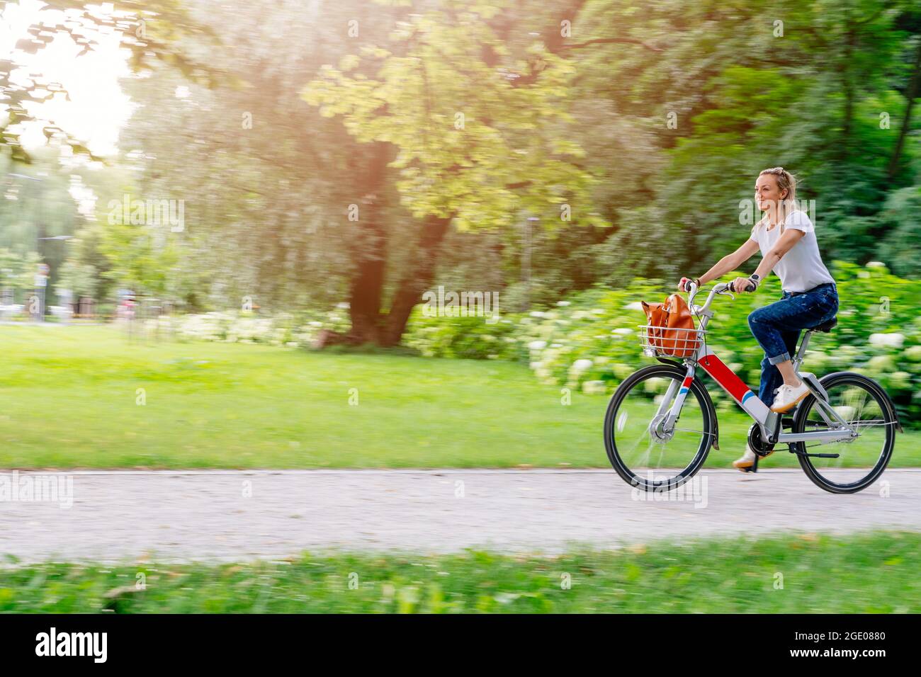 Belle et gaie femme adulte profiter de vélo dans une ville ensoleillée de loisirs en plein air activité dans la ville. Banque D'Images