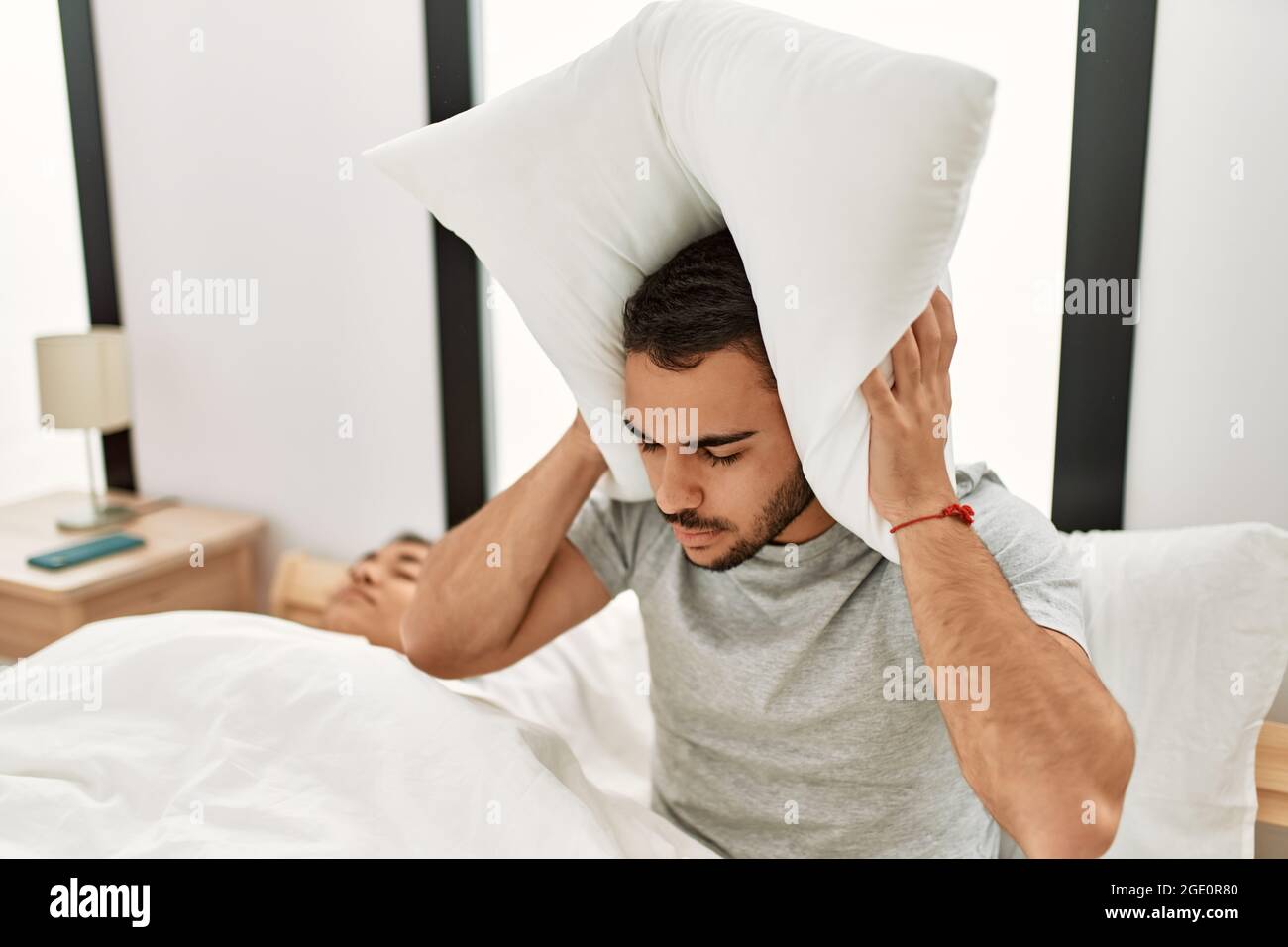 Homme couvrant les oreilles avec l'oreiller irrité pour le museau couché dans  le lit à la maison Photo Stock - Alamy