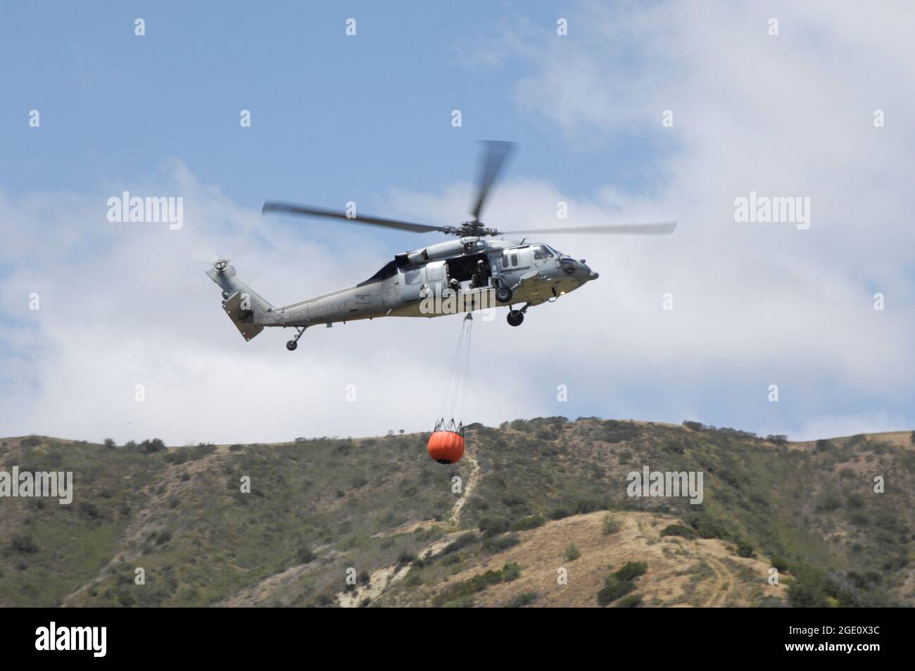 Un U S Navy MH60S se dirige vers la zone de chute avec un baquet Bambi complet à bord du MCB Camp Pendleton, Californie Banque D'Images Un U S Navy MH60S se dirige vers la zone de chute avec un baquet Bambi complet à bord du MCB Camp Pendleton, Californie Banque D'Images