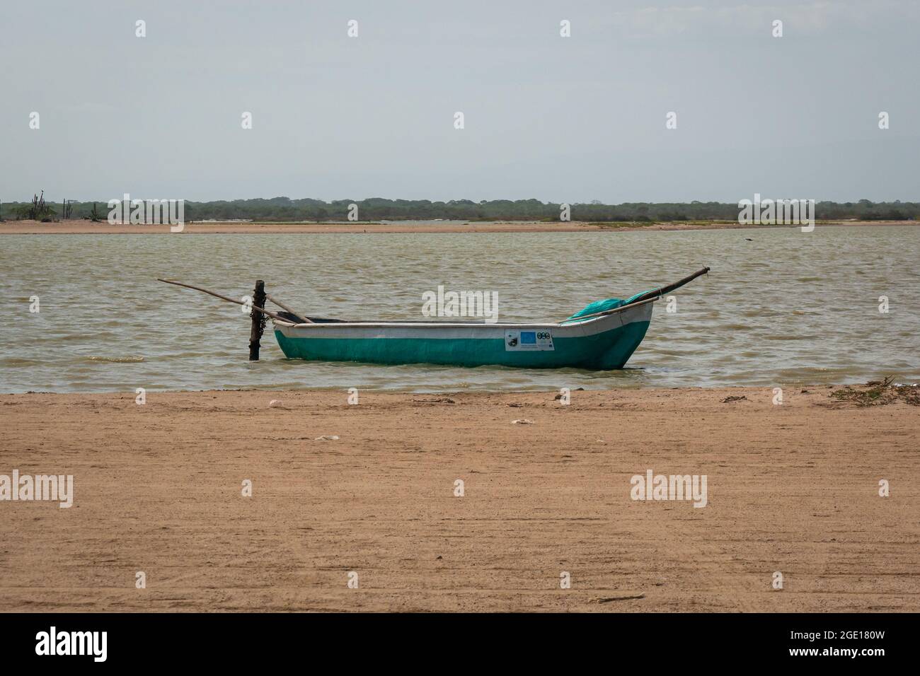 Riohacha, la Guajira, Colombie - Mai 30 2021 : petit bateau blanc et vert attaché à un bâton de bois près de la plage de sable à Camarones Banque D'Images