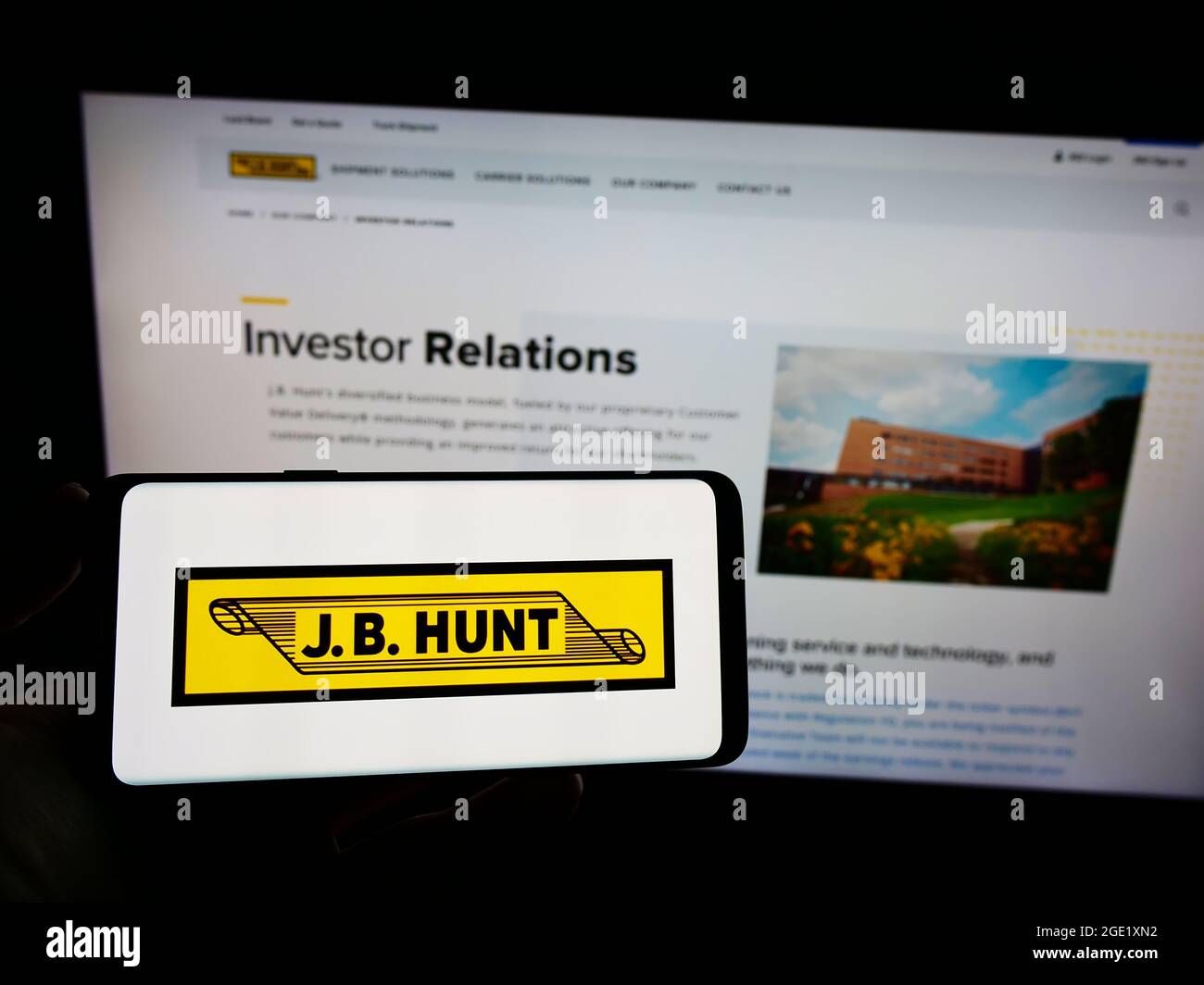 Personne tenant un téléphone portable avec le logo de la société logistique J.B. Hunt transport Services Inc. À l'écran en face de la page Web. Mise au point sur l'affichage du téléphone. Banque D'Images