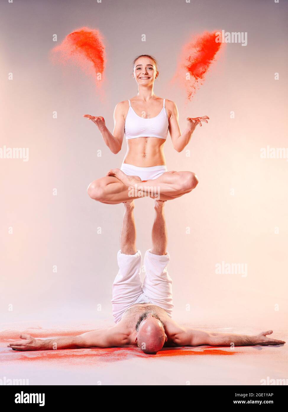 Belle femme sportive et homme dans des vêtements blancs faisant des asanas de yoga avec le sable coloré intérieur Banque D'Images