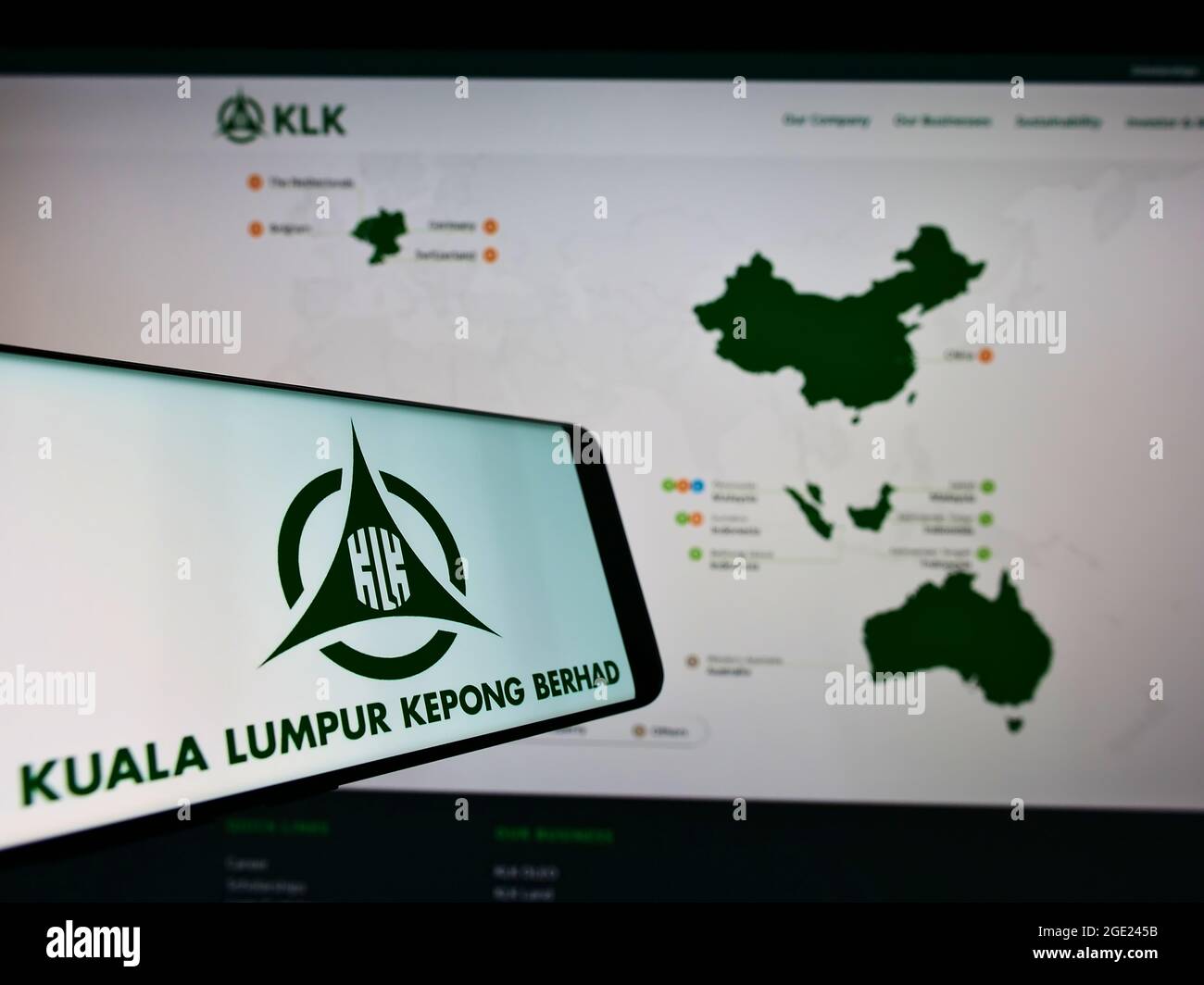 Téléphone portable avec logo de la société malaisienne Kuala Lumpur Kepong Berhad (KLK) à l'écran devant le site. Effectuez la mise au point au centre-droit de l'écran du téléphone. Banque D'Images