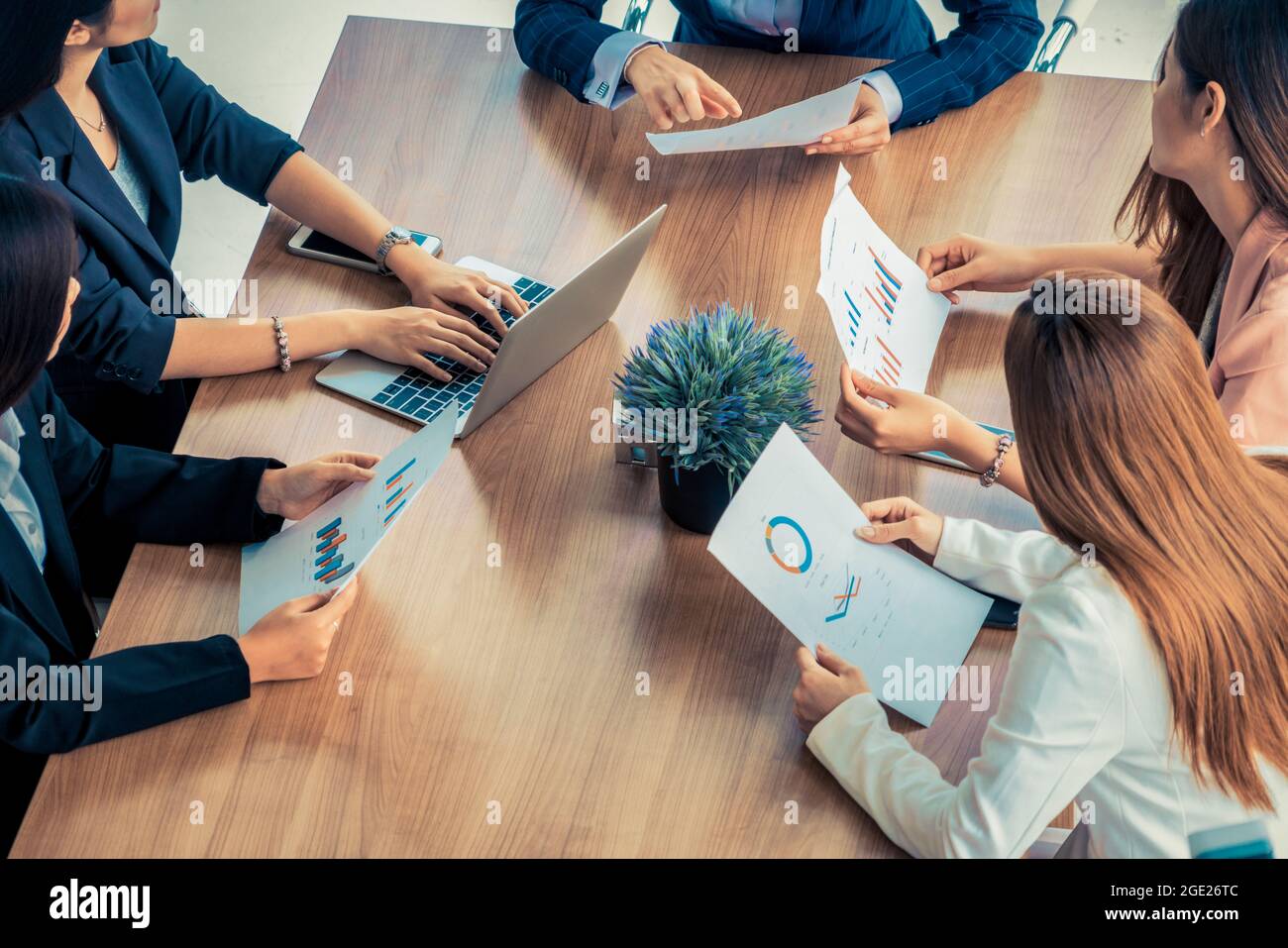 Femme d'affaires dans la discussion de réunion de groupe avec d'autres femmes d'affaires collègues dans bureau moderne avec ordinateur portable et documents sur table Banque D'Images