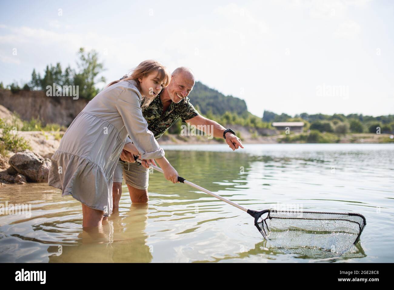 Bonne fille et grand-père de la préadolescence avec filet de pêche sur les vacances d'été au bord du lac. Banque D'Images