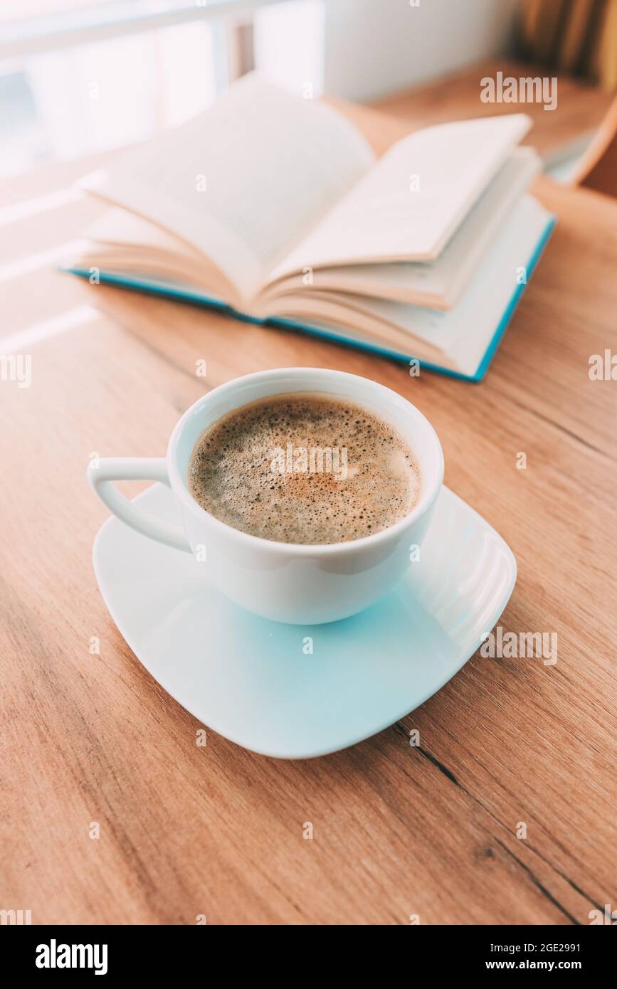 Tasse de café sur la table, livre ouvert en arrière-plan, sélection Banque D'Images