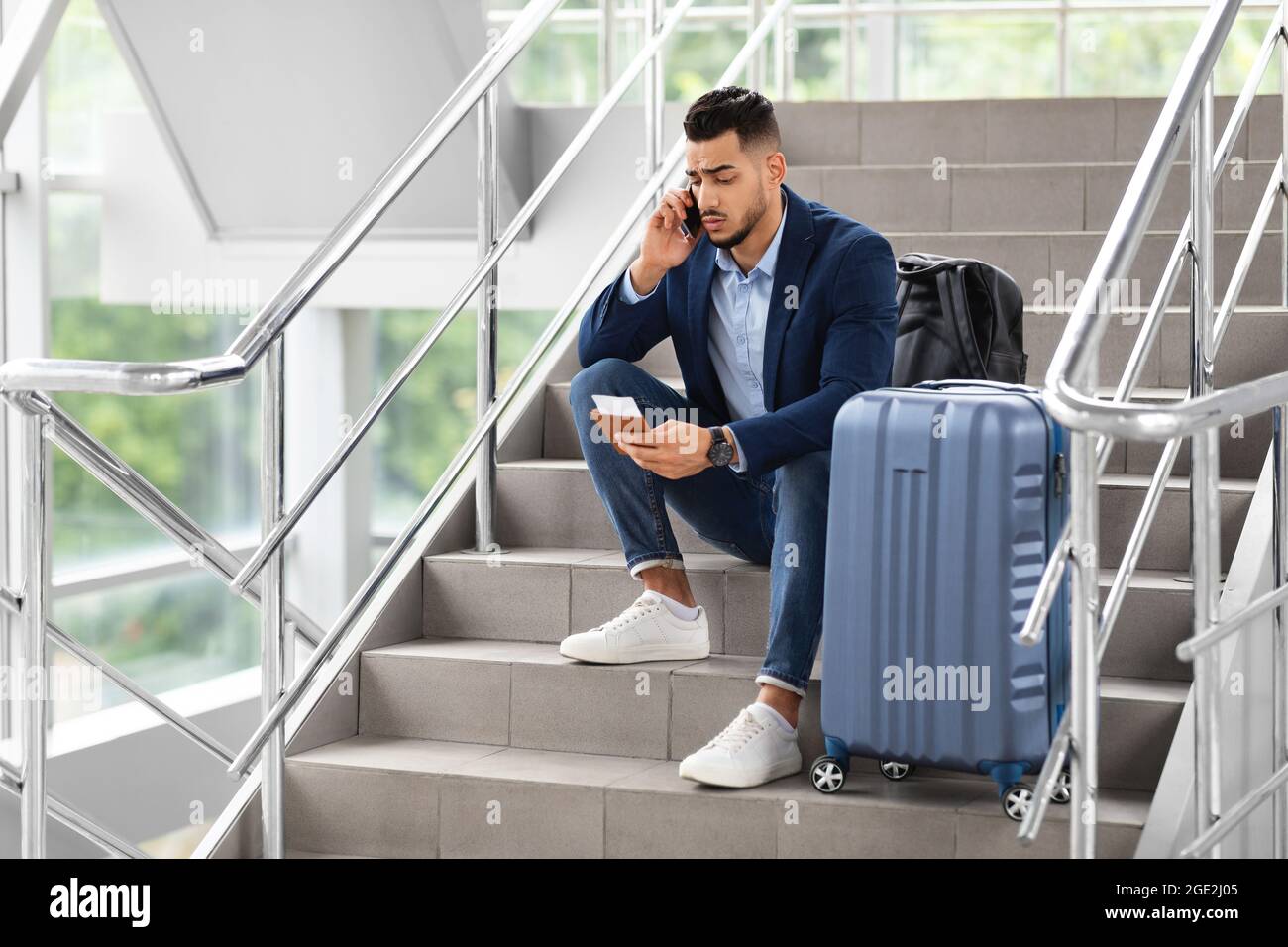 Vol retardé. Inquiet Homme assis sur les escaliers de l'aéroport, parlant sur le téléphone portable Banque D'Images