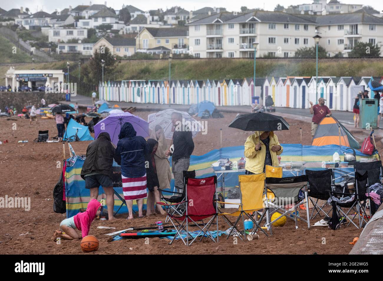 Les vacanciers brave les éléments à Goodrington North Beach à Paignton, Devon, frappé par des averses orageuses obligeant certains touristes à courir pour couvrir, Royaume-Uni. Banque D'Images