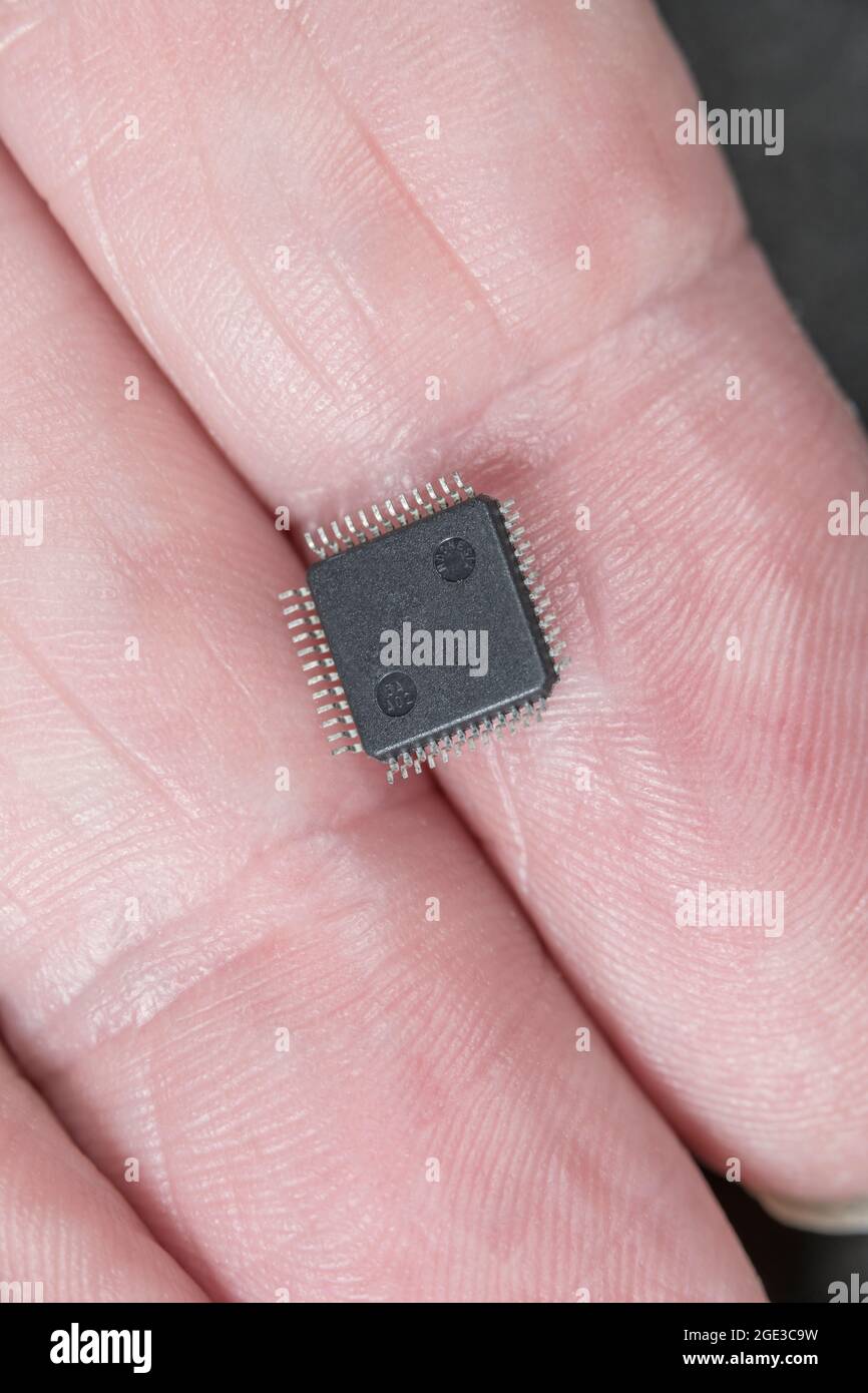 Gros plan sur le dessous de la petite puce de circuit intégré / ci sur les doigts montrant la petite taille de composant et les jambes en M. Il s'agit d'un IC audio MP3 / WMA. Banque D'Images