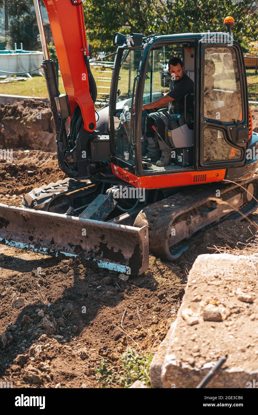 Travailleur conduisant une pelle hydraulique sur un chantier de construction. Banque D'Images