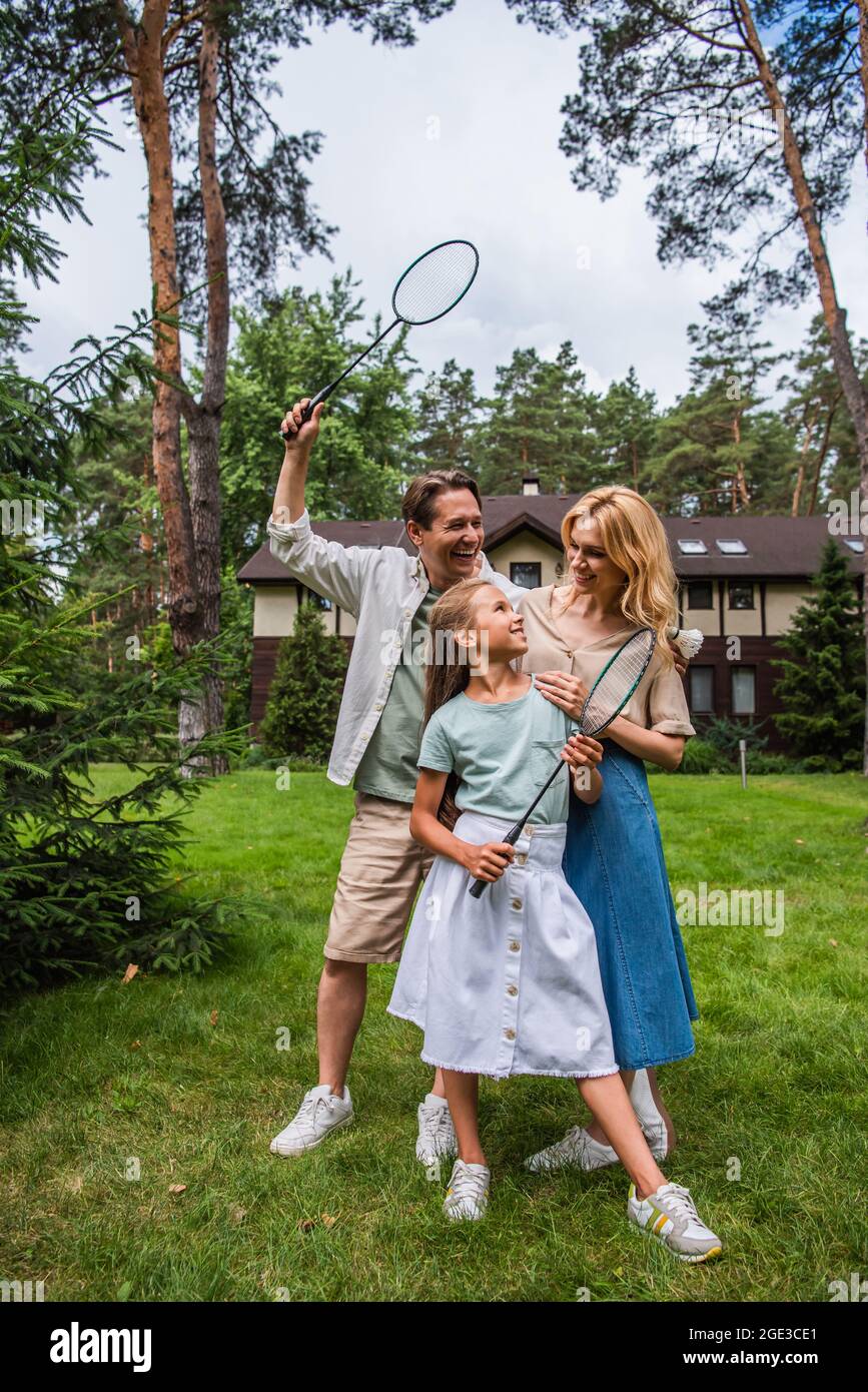 Famille souriante avec des raquettes de badminton qui embrasent sur la pelouse Banque D'Images