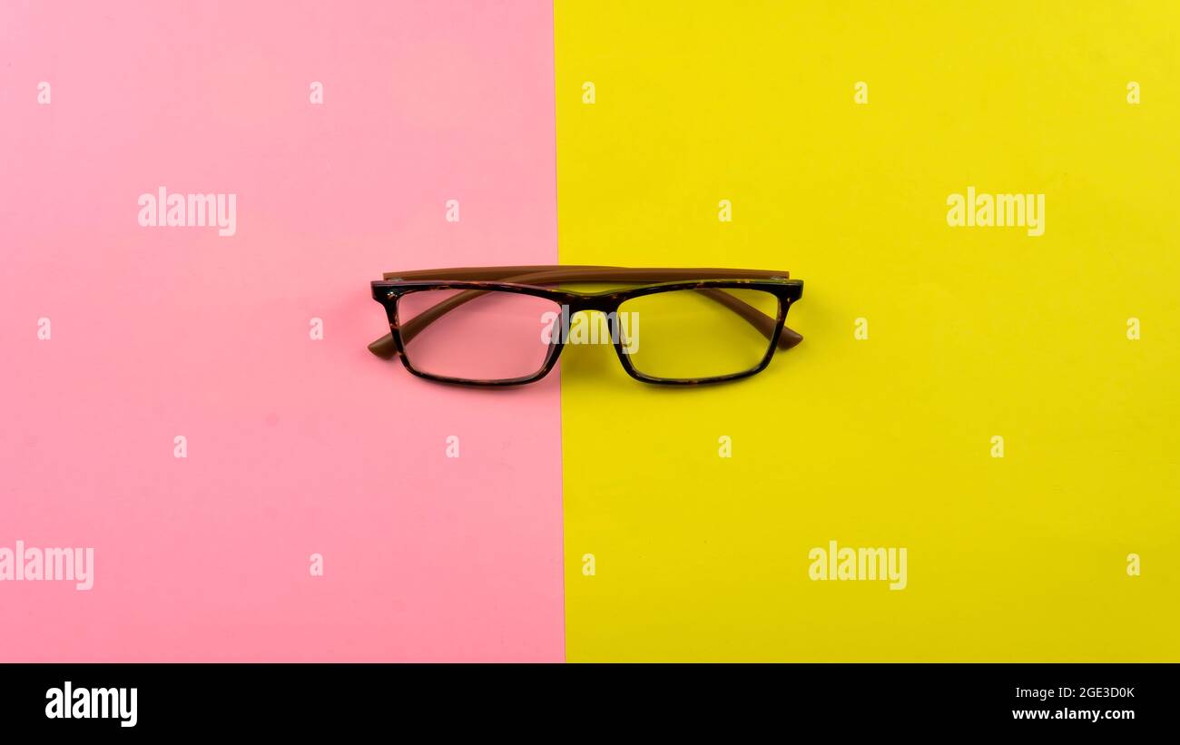 Un concept de soins oculaires. La Sélétive se concentre sur des lunettes sur fond jaune et rose Banque D'Images