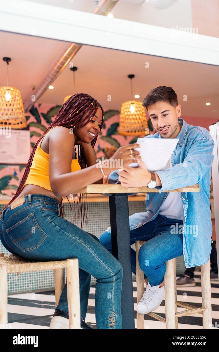 Amis multiculturels assis dans un restaurant et lisant le menu ensemble. Banque D'Images