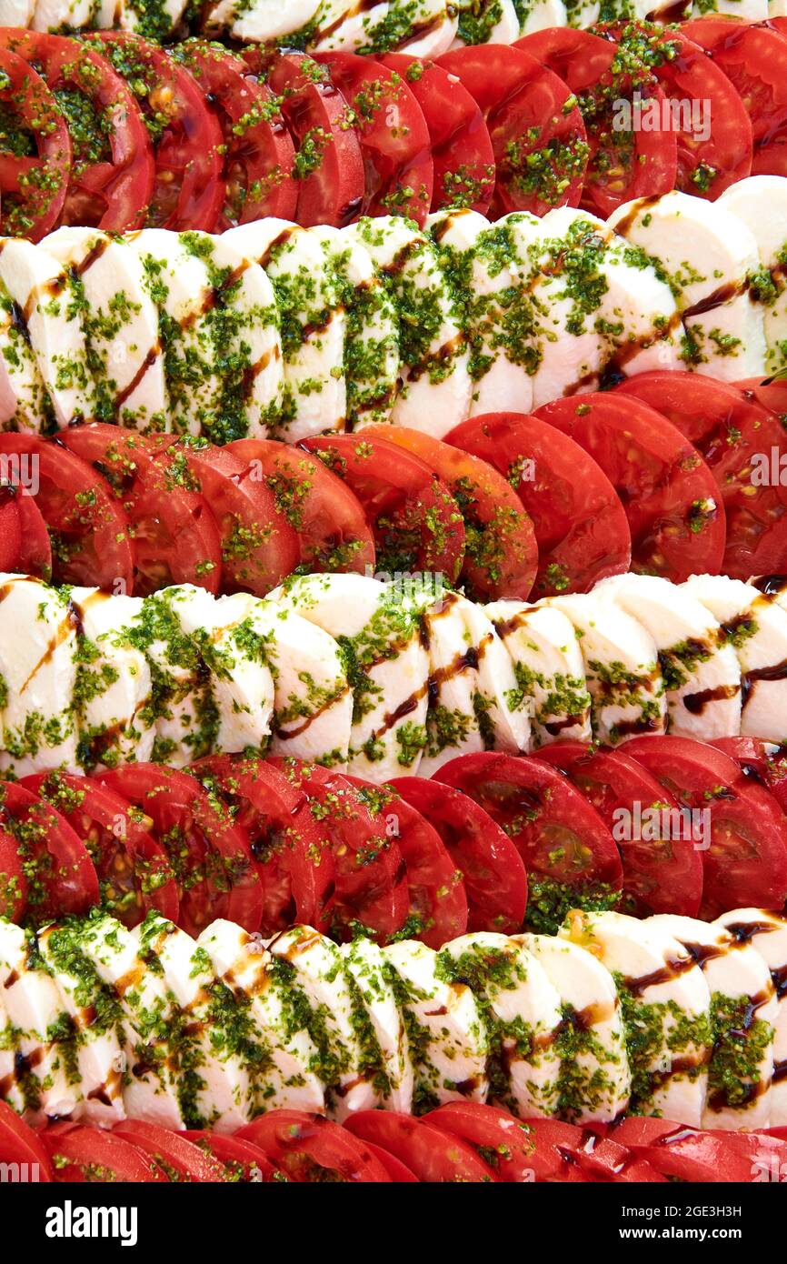 Fond de salade Caprese. Beaucoup de tomates tranchées et de fromage mozzarella recouverts de sauce pesto. Photo de concept de mode de vie sain. La cuisine est magnifique Banque D'Images