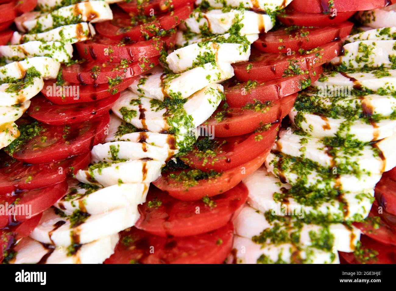 Fond de salade Caprese. Beaucoup de tomates tranchées et de fromage mozzarella recouverts de sauce pesto. Photo de concept de mode de vie sain. La cuisine est magnifique Banque D'Images