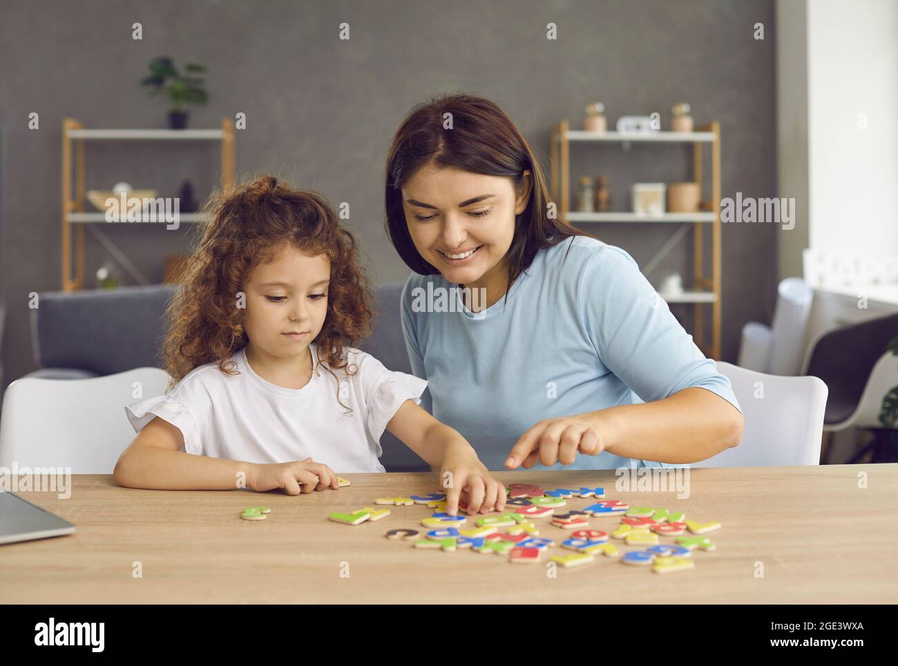 Bonne petite fille apprenant l'alphabet anglais avec sa mère, son professeur ou son tuteur à la maison Banque D'Images