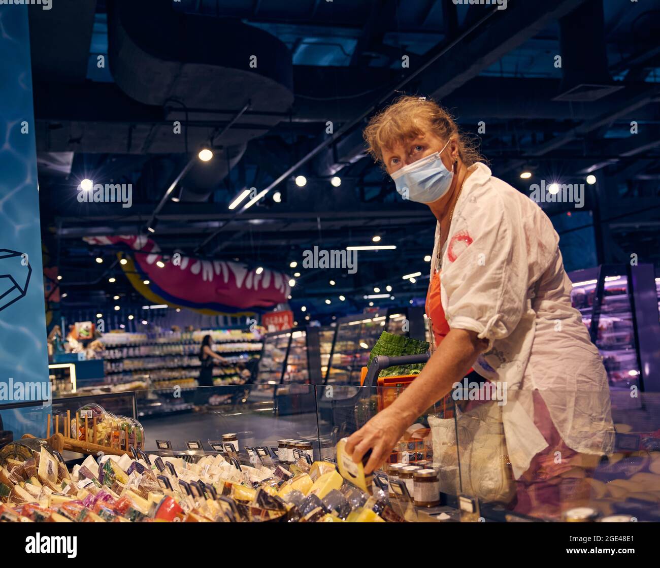 Une jolie femme âgée dans un masque médical choisit du fromage dans une épicerie. Odessa Ukraine, magasin d'alimentation Silpo. Banque D'Images