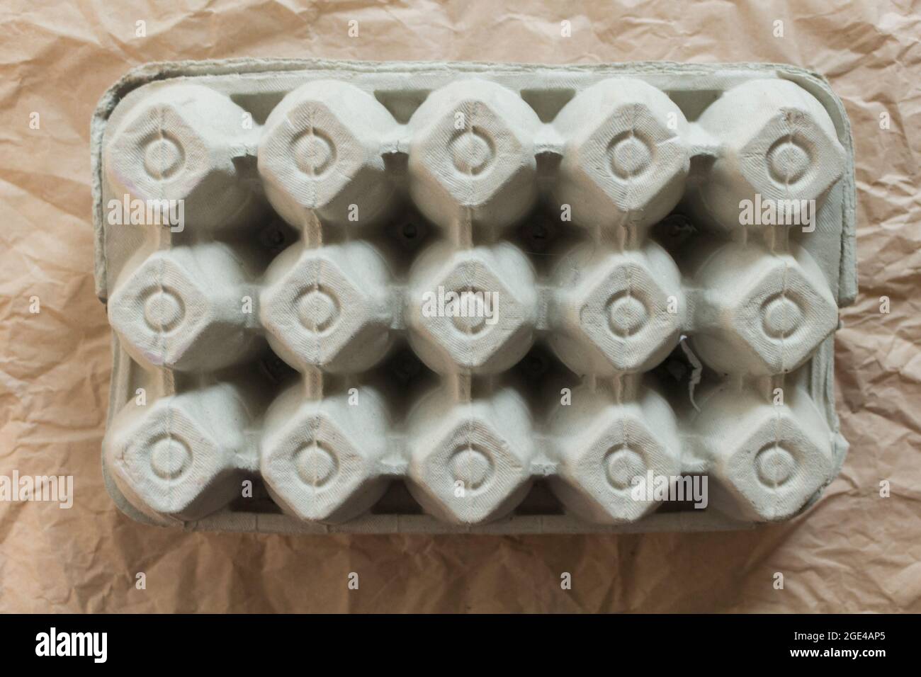 Boîte en carton d'œufs fermée isolée sur fond de papier kraft froissé. Vue de dessus de l'emballage en carton d'œufs de poulet biologique ou du récipient à œufs. Banque D'Images
