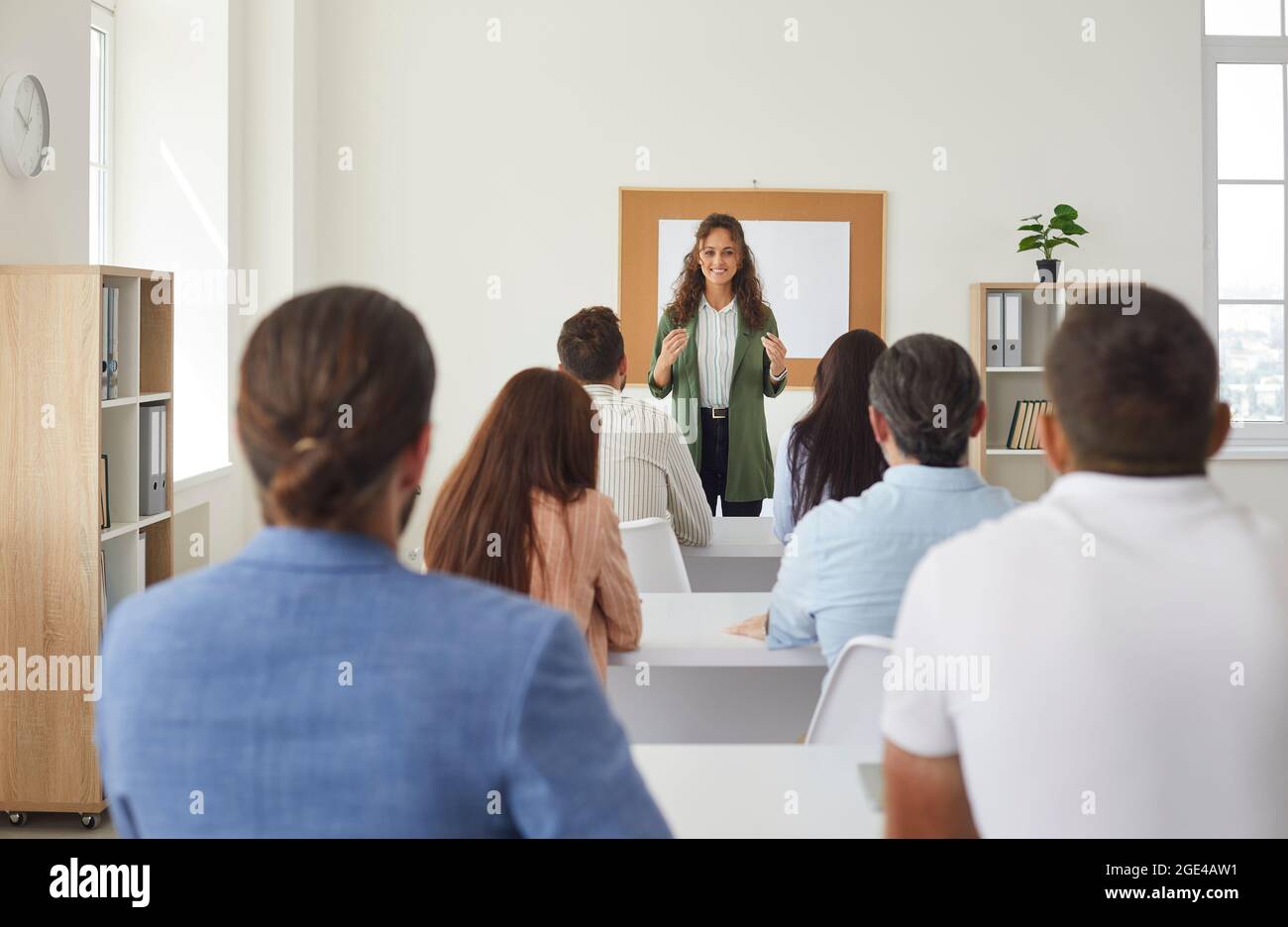 Vue arrière d'un groupe d'élèves adultes assis en classe et à l'écoute d'un enseignant Banque D'Images