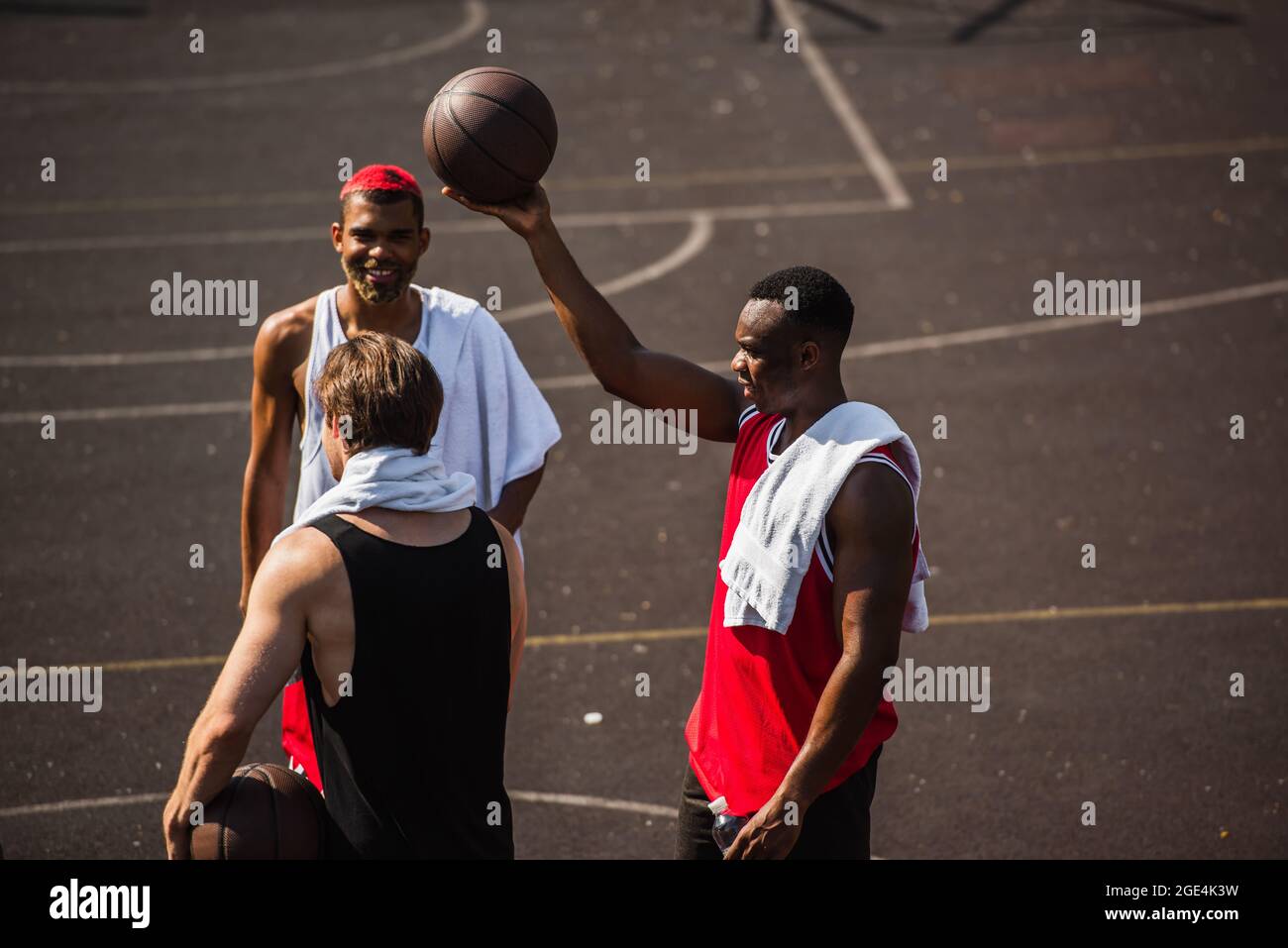 Sportifs interraciaux avec des serviettes et des balles de basket-ball à l'extérieur Banque D'Images