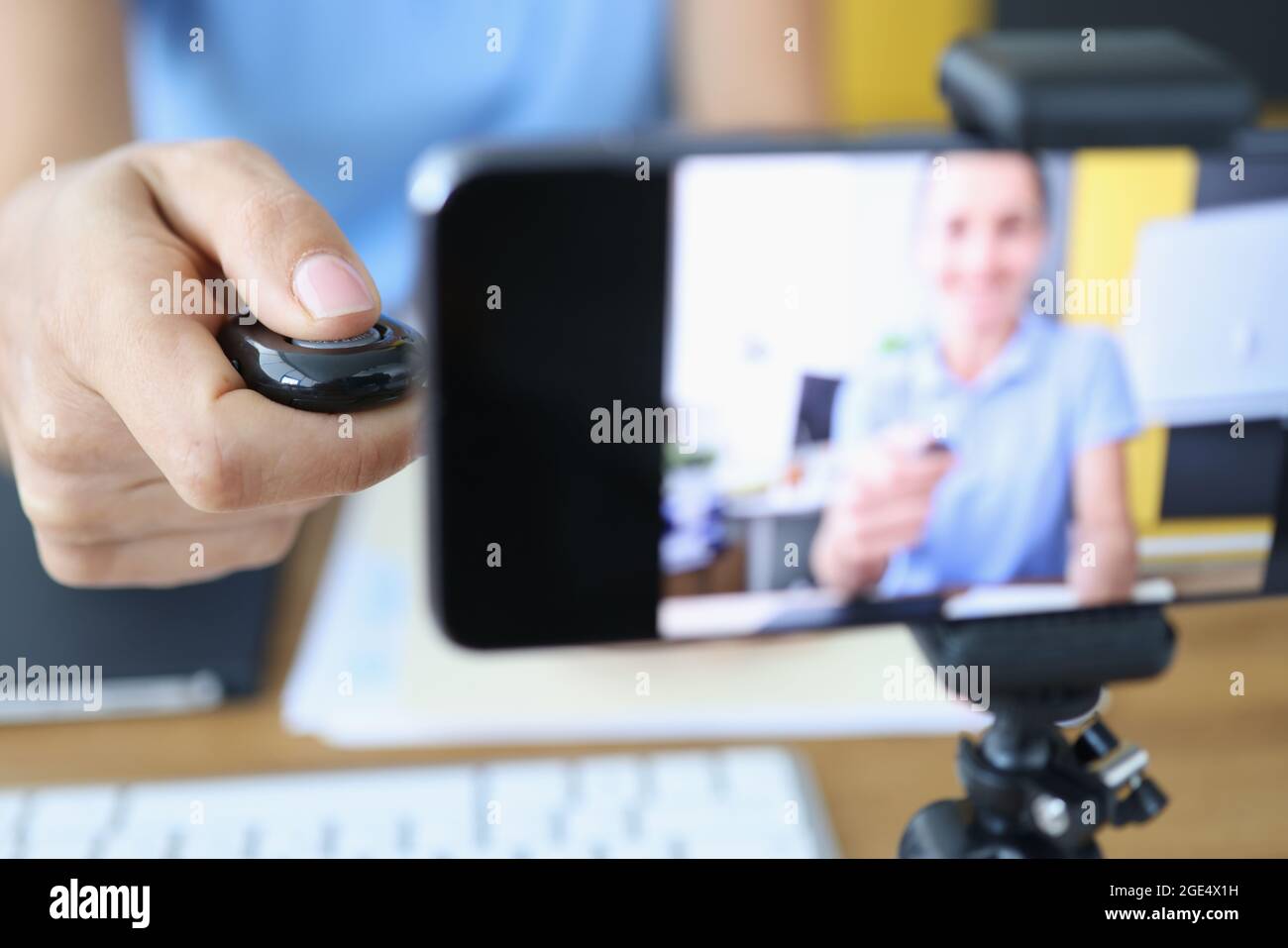 Femme appuie sur le bouton du panneau de commande et enregistre des vidéos sur smartphone sur trépied Banque D'Images